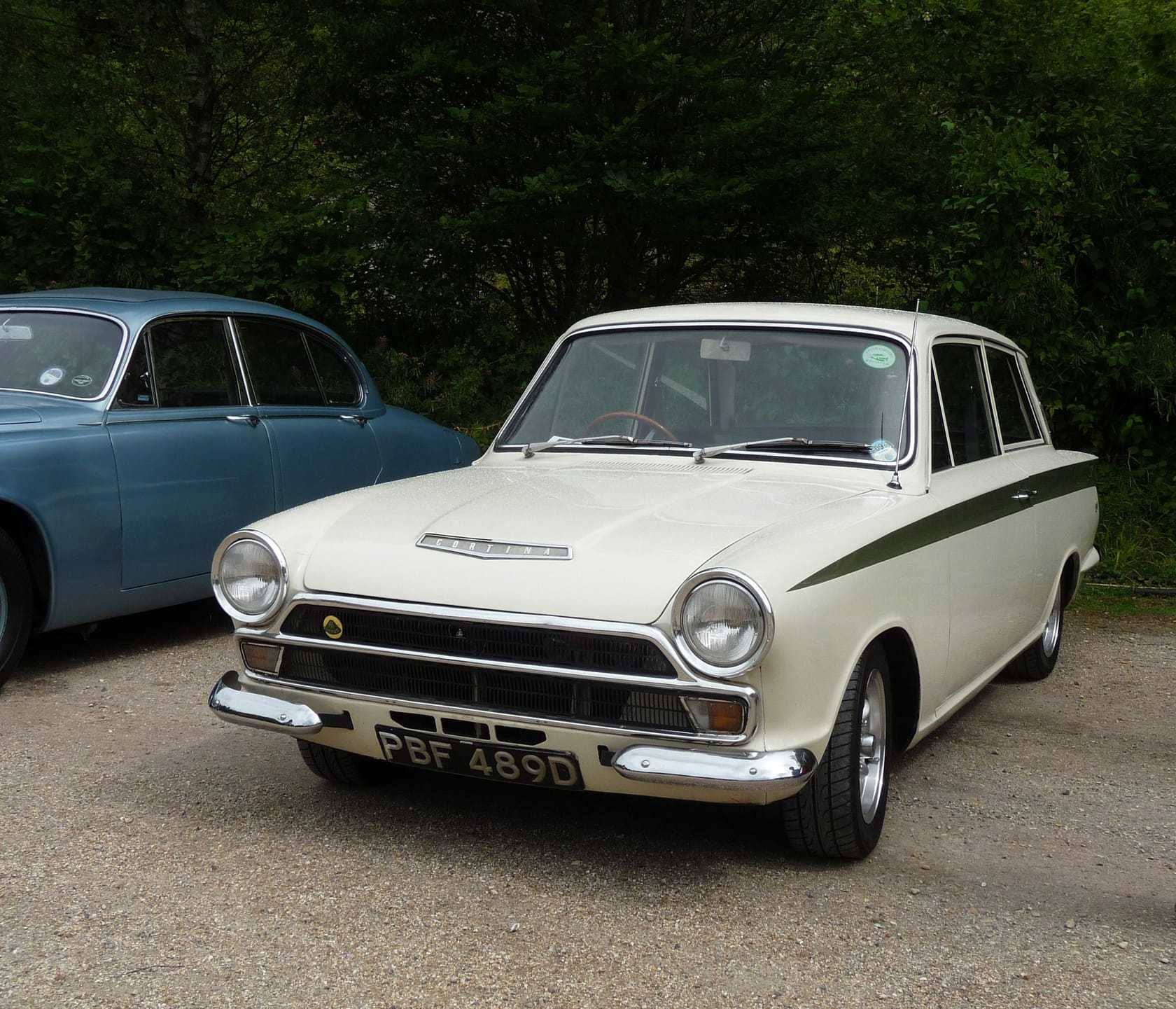 A white 1966 Lotus Cortina Mk1 with green side flash, front three-quarter view outdoors