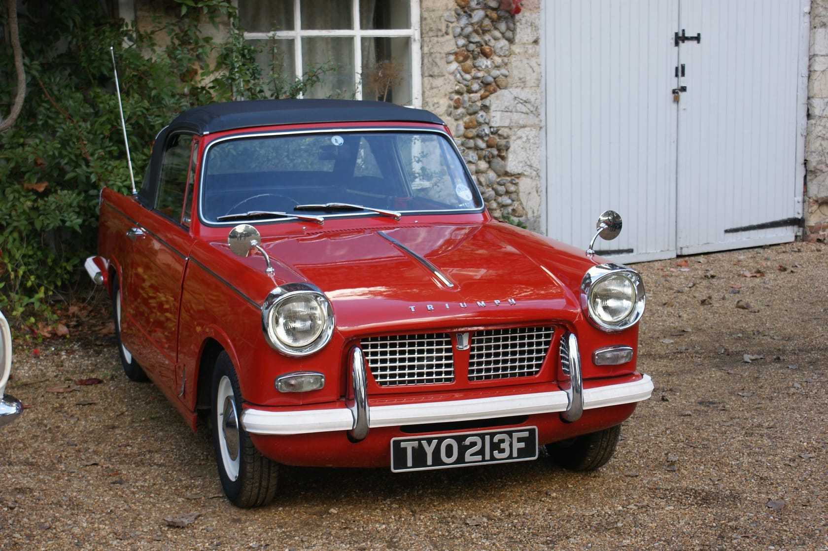 A red Triumph Herald 1200 convertible with the top down, front three-quarter view