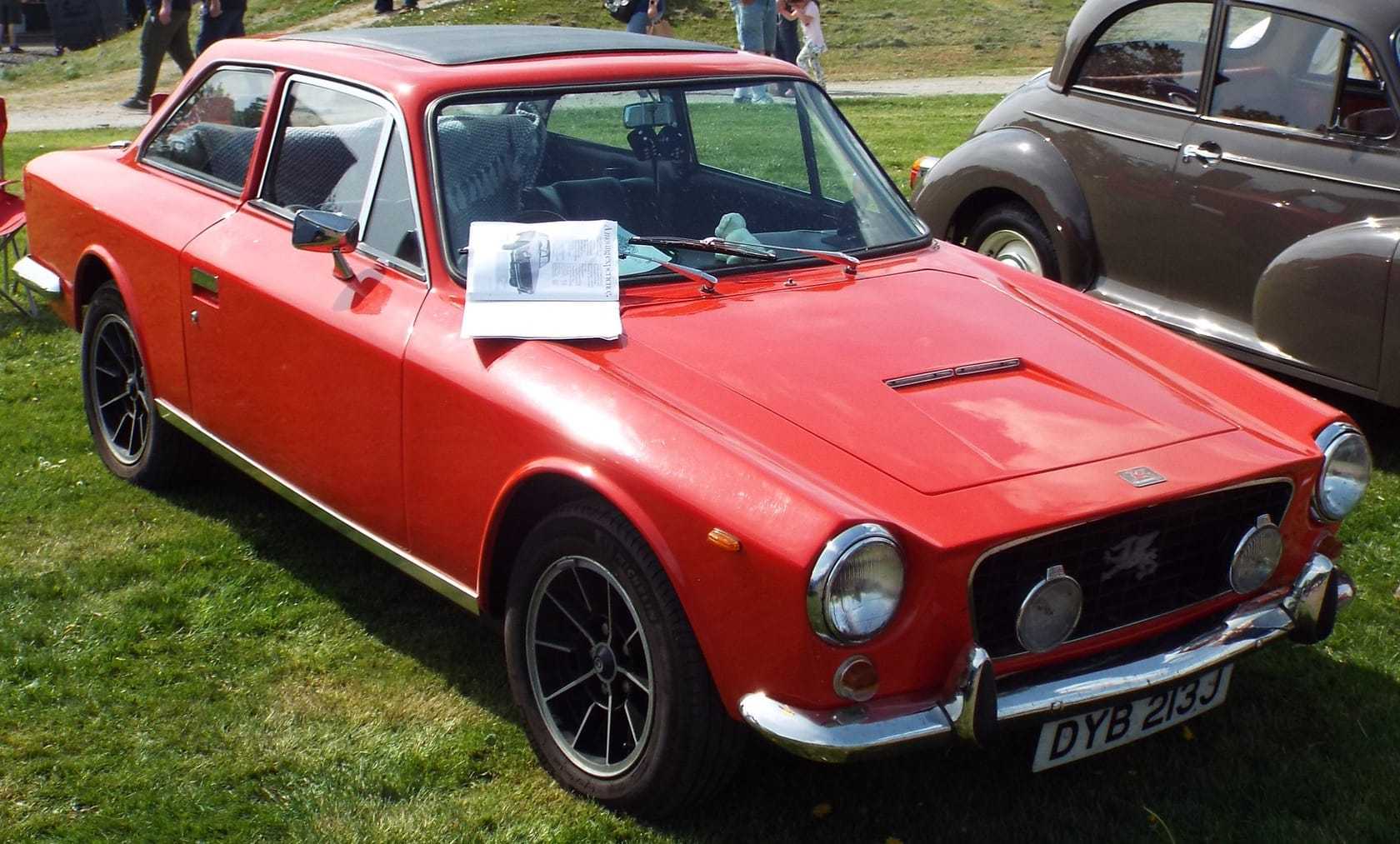 A red Gilbern Invader, a British glass-fibre kit-built grand tourer, front three-quarter view at a classic car show