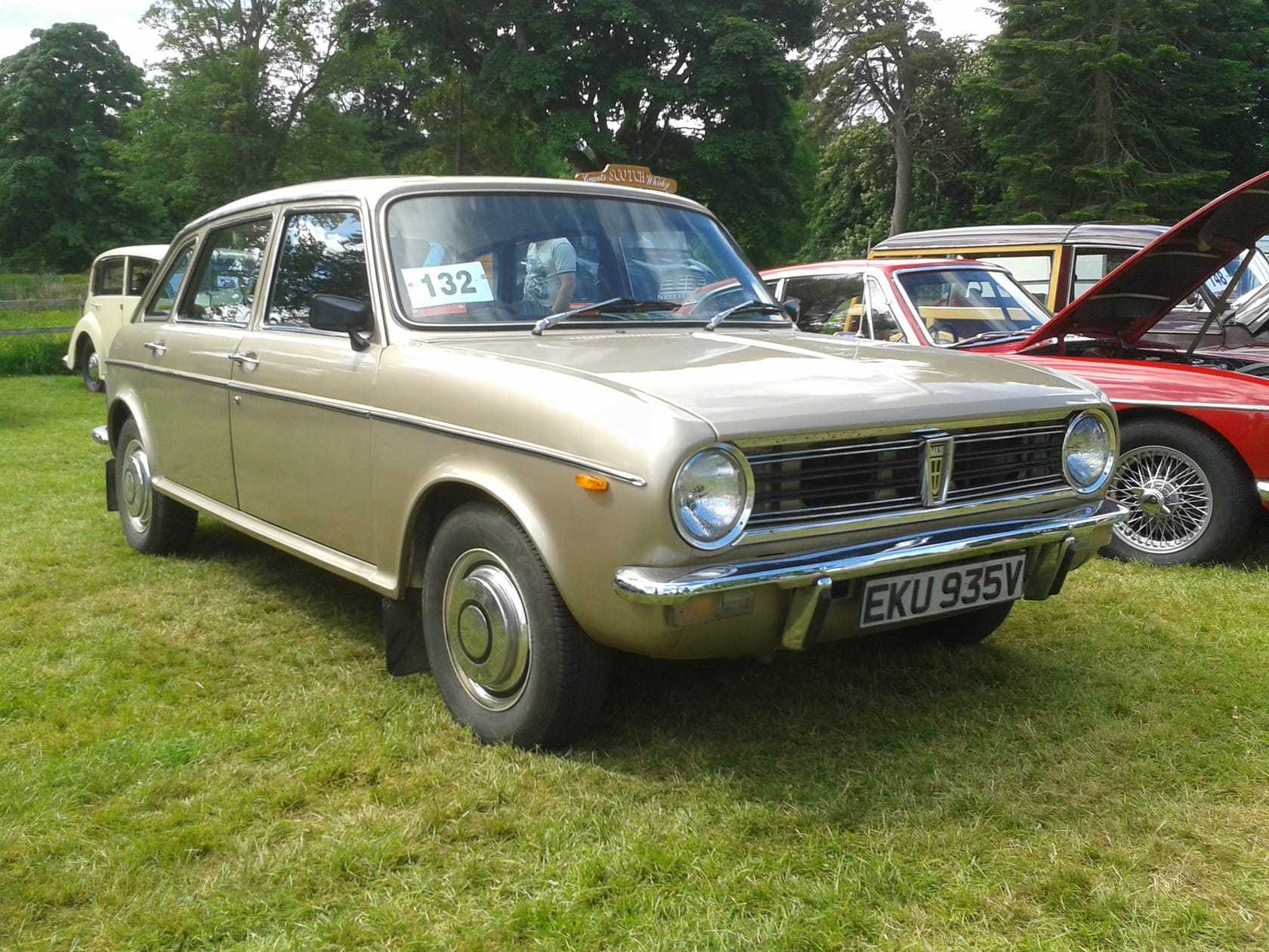 A blue 1980 Austin Maxi HLS parked on grass at a classic car show, front three-quarter view