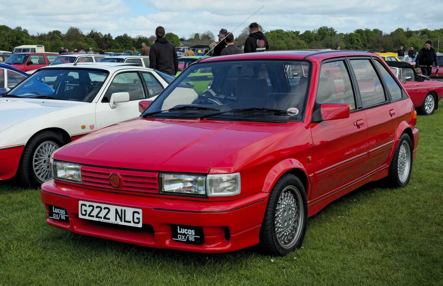 A red 1989 MG Maestro Turbo with its Tickford bodykit and a UK registration on a show field