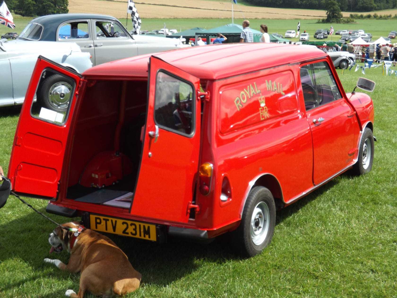 A red Mini Van in Royal Mail livery with its rear doors open, at a show