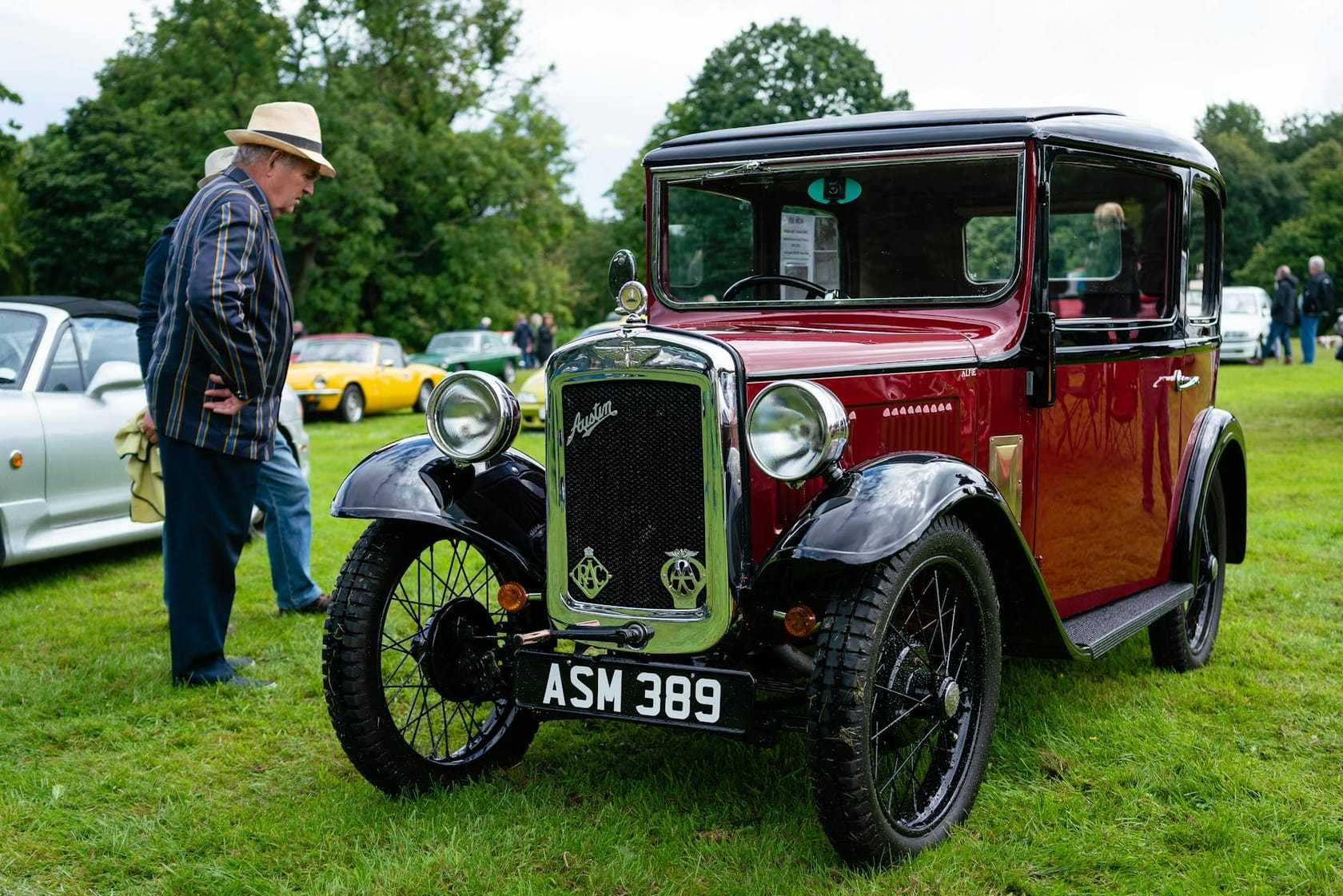 A maroon and black Austin Seven Ruby saloon at a show, front three-quarter view, UK registration ASM 389