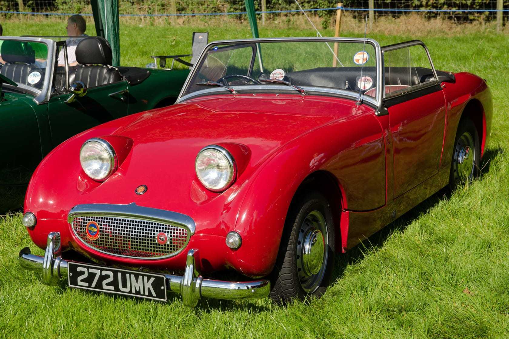 A red 1959 Austin-Healey Frogeye Sprite with a UK registration on a show field