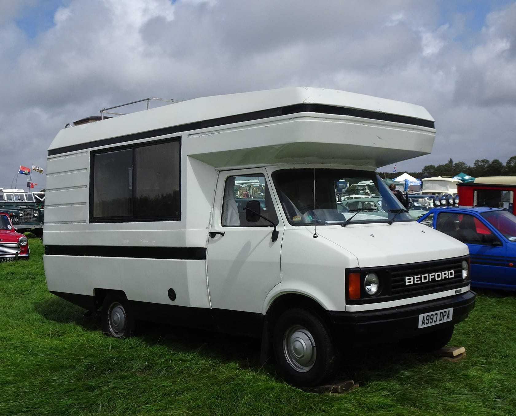 A white Bedford CF Auto-Sleeper coachbuilt motorhome on grass at a show, side three-quarter view showing the CF cab and the BEDFORD grille badge