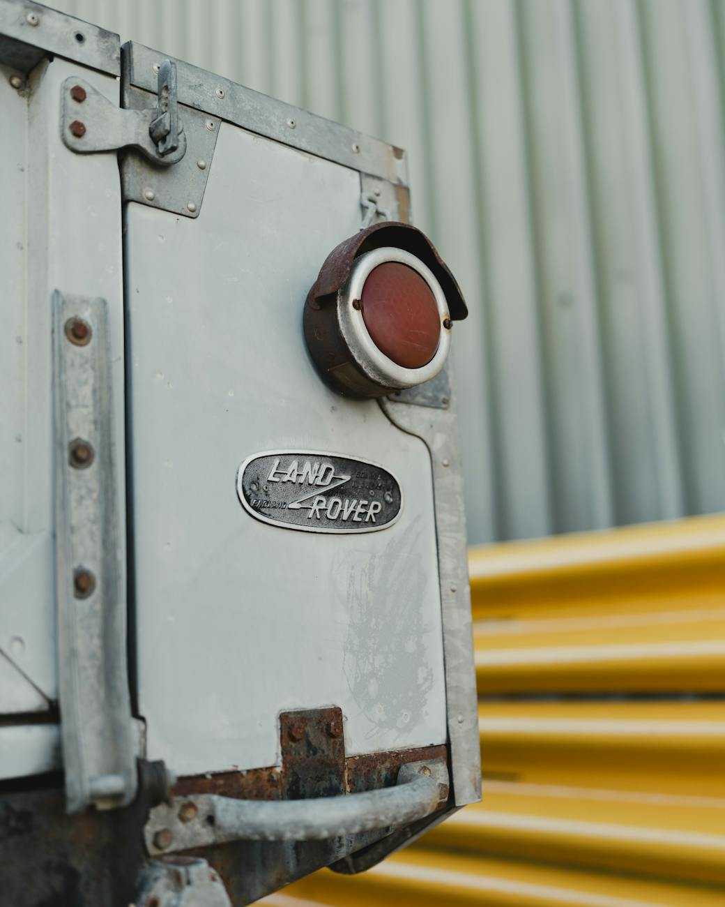 Close-up of the round tail lamp and badge on a weathered aluminium Land Rover panel