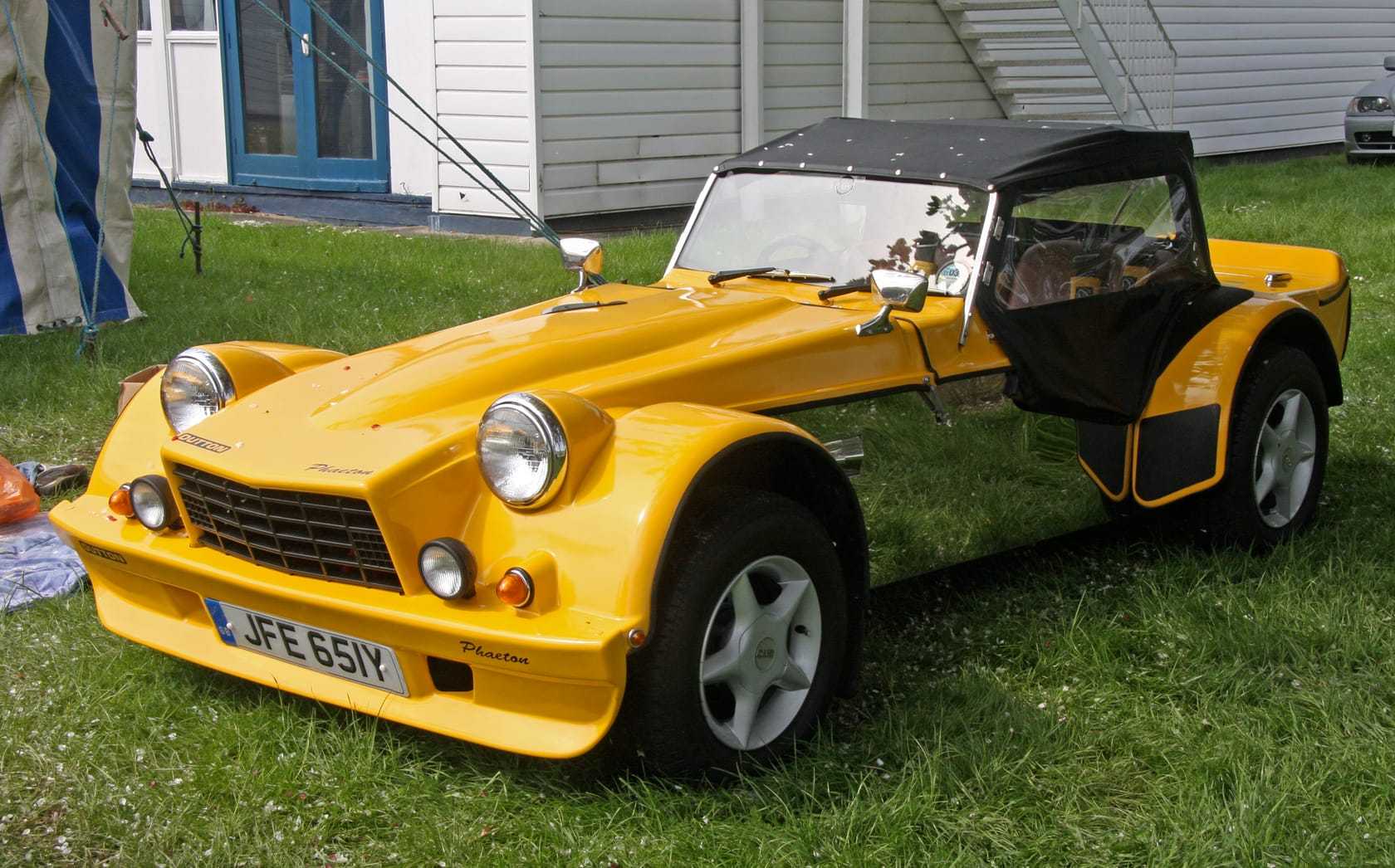 A green Dutton Phaeton cycle-winged open roadster with a yellow nose, registration YVM 830M, front three-quarter view on grass