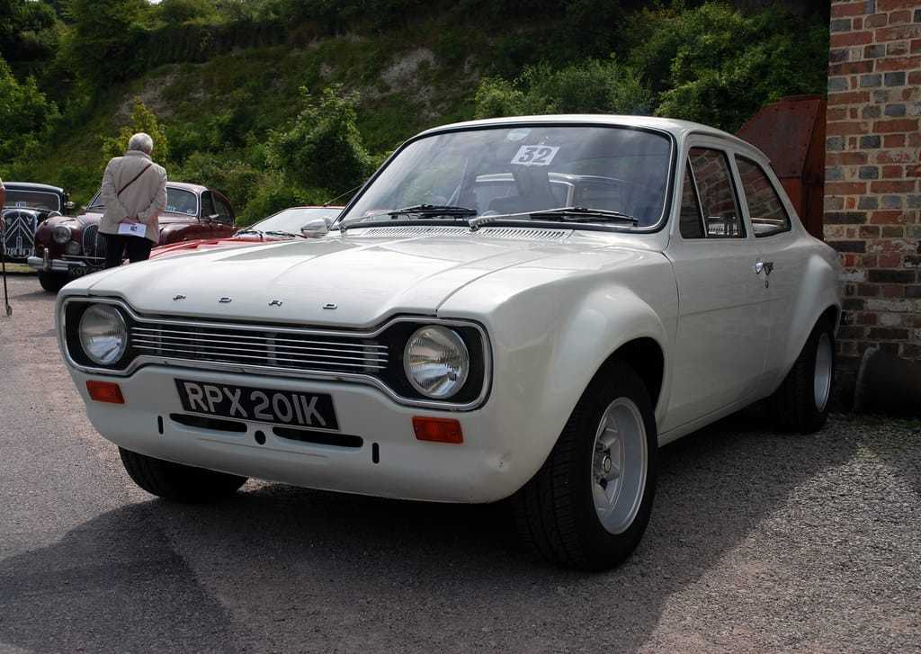 A white Ford Escort Mk1 two-door with UK registration RPX 201K, front three-quarter view at a classic car show