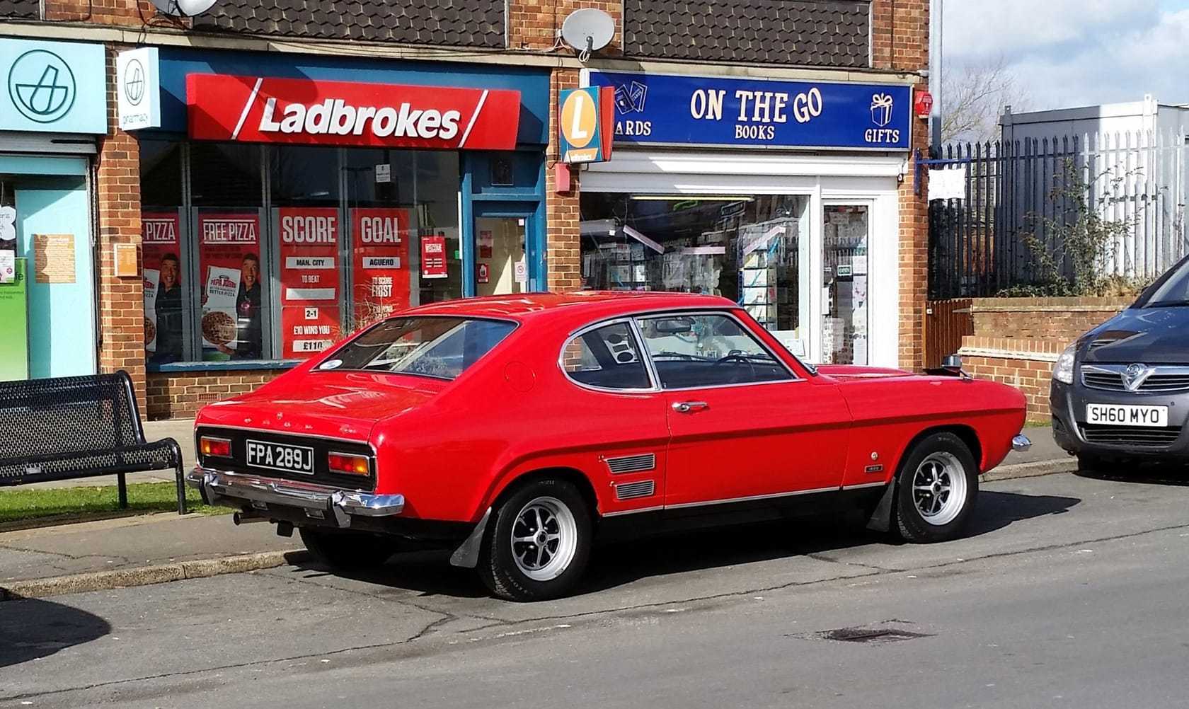 A red Mk1 Ford Capri parked on a British street, rear three-quarter view