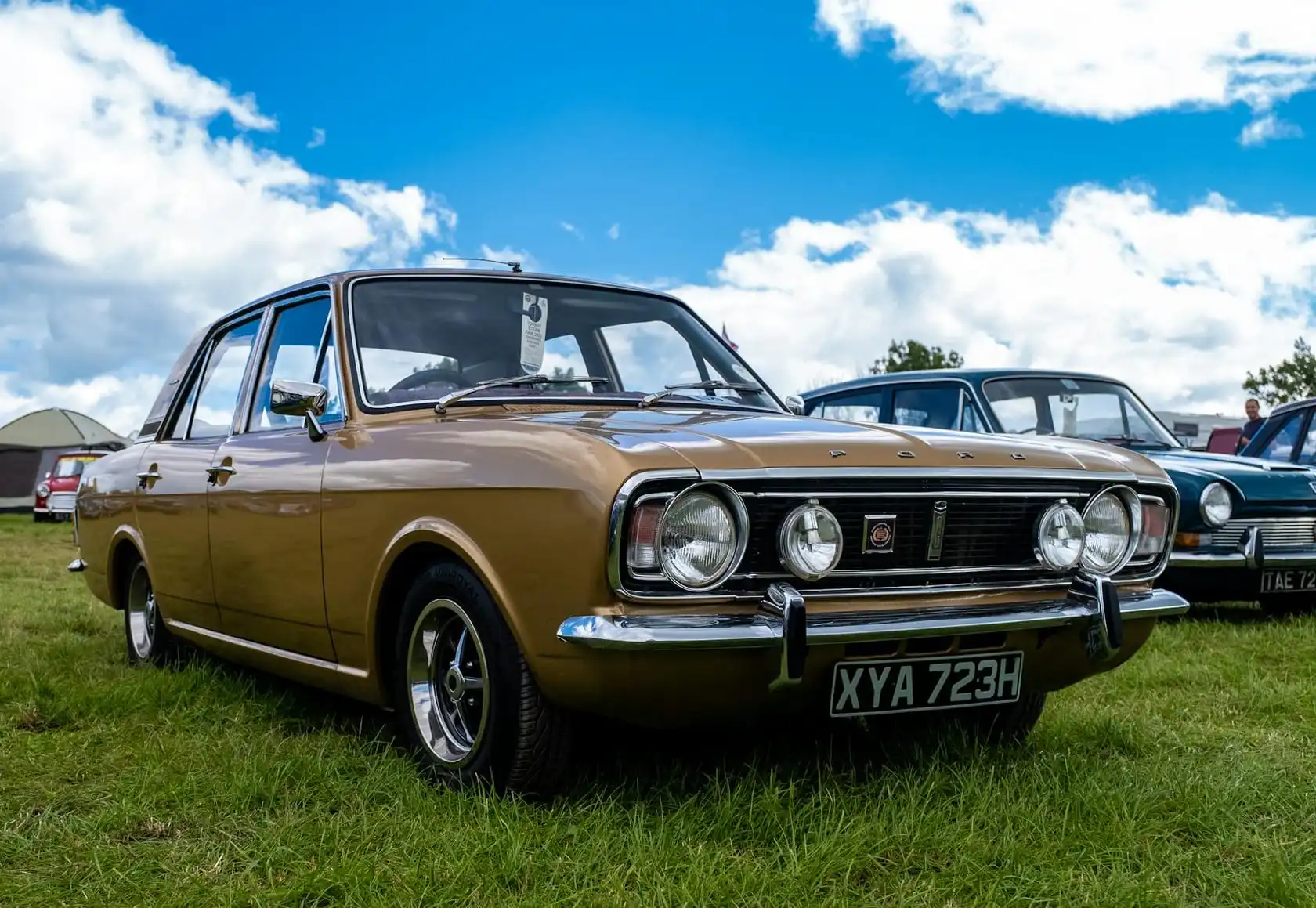 A gold Ford Cortina Mk2 four-door saloon at a show, front three-quarter view