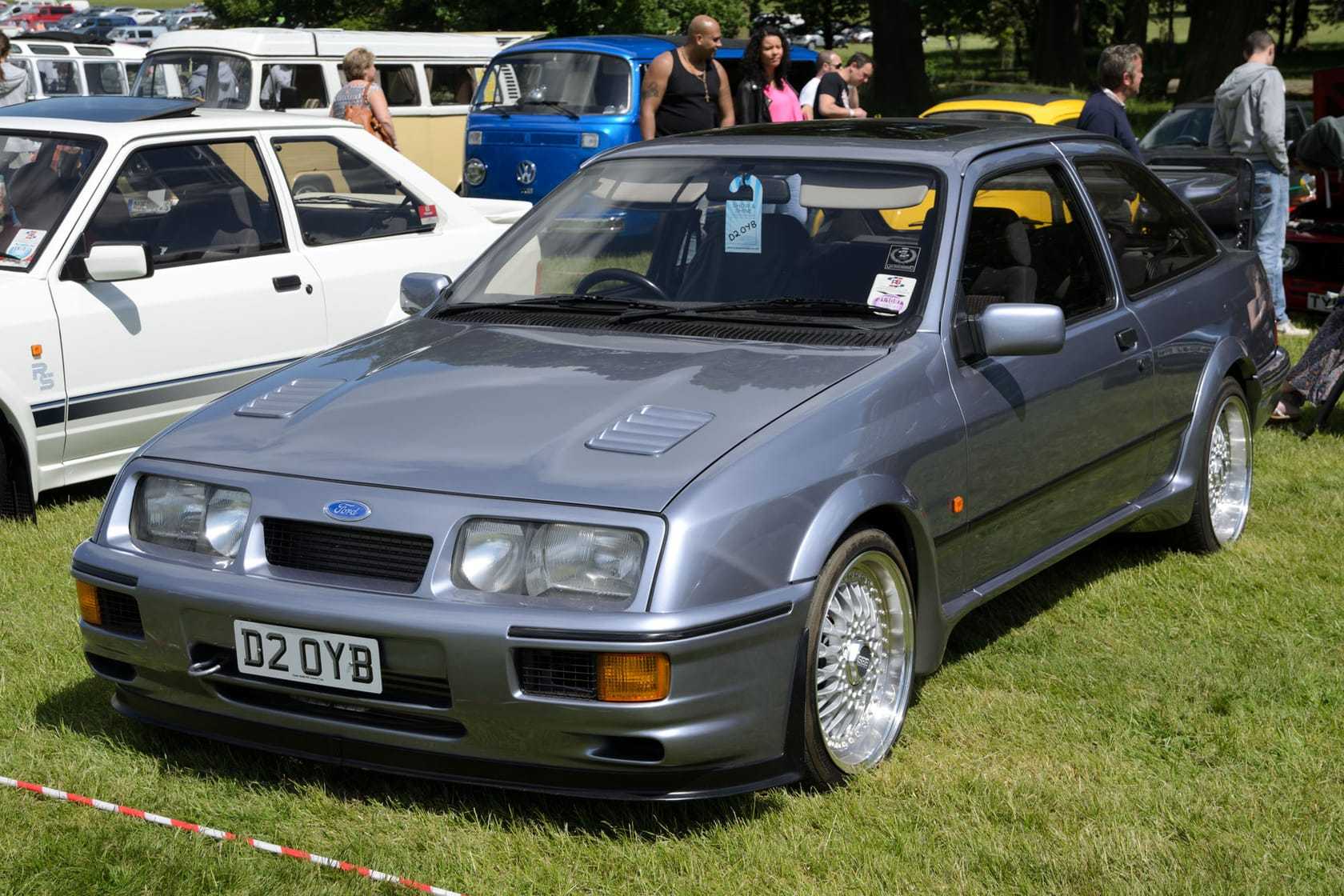 A grey three-door Ford Sierra RS Cosworth with a whale-tail wing, front three-quarter view