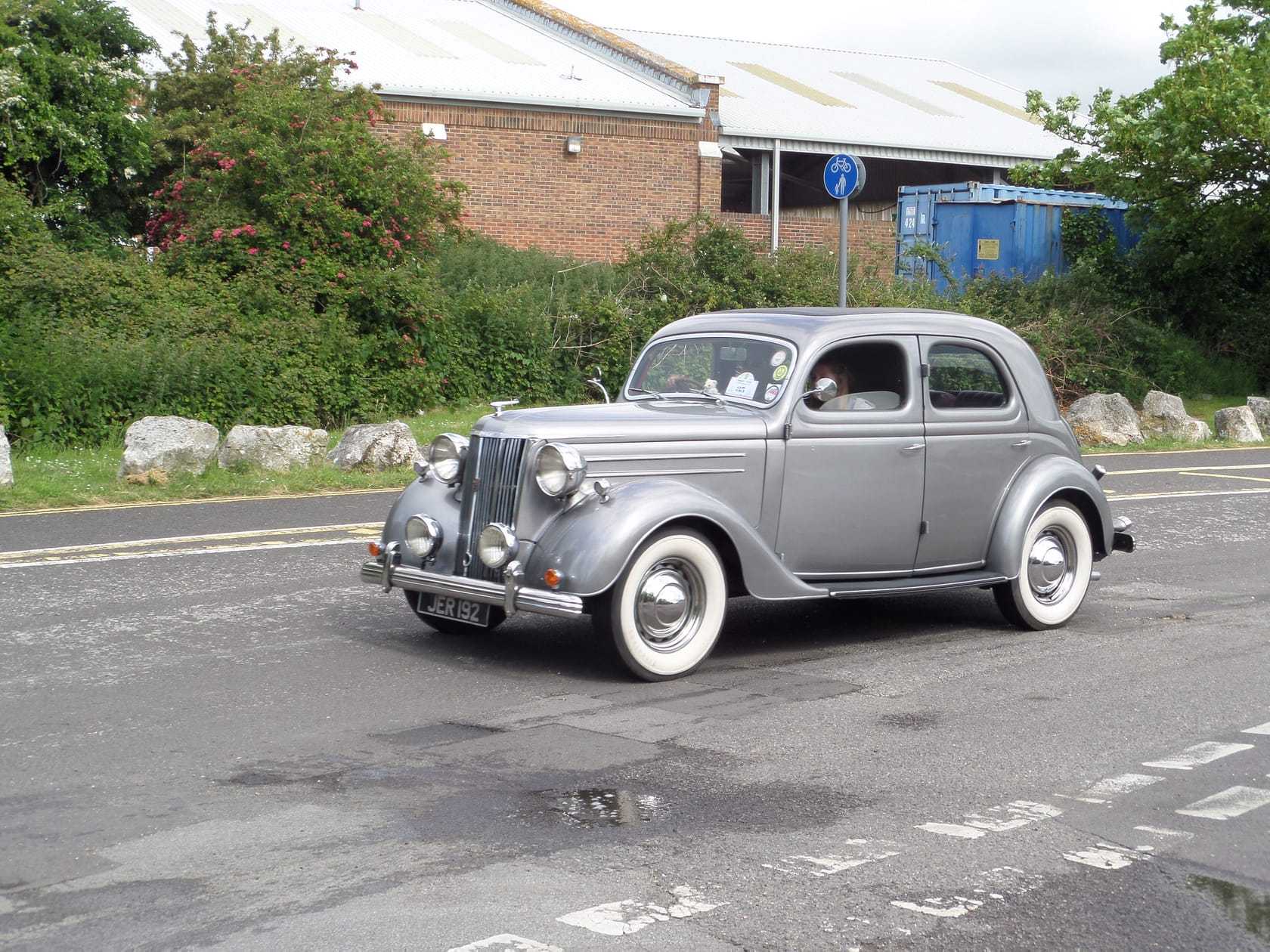 A grey Ford V8 Pilot saloon on a road, front three-quarter view