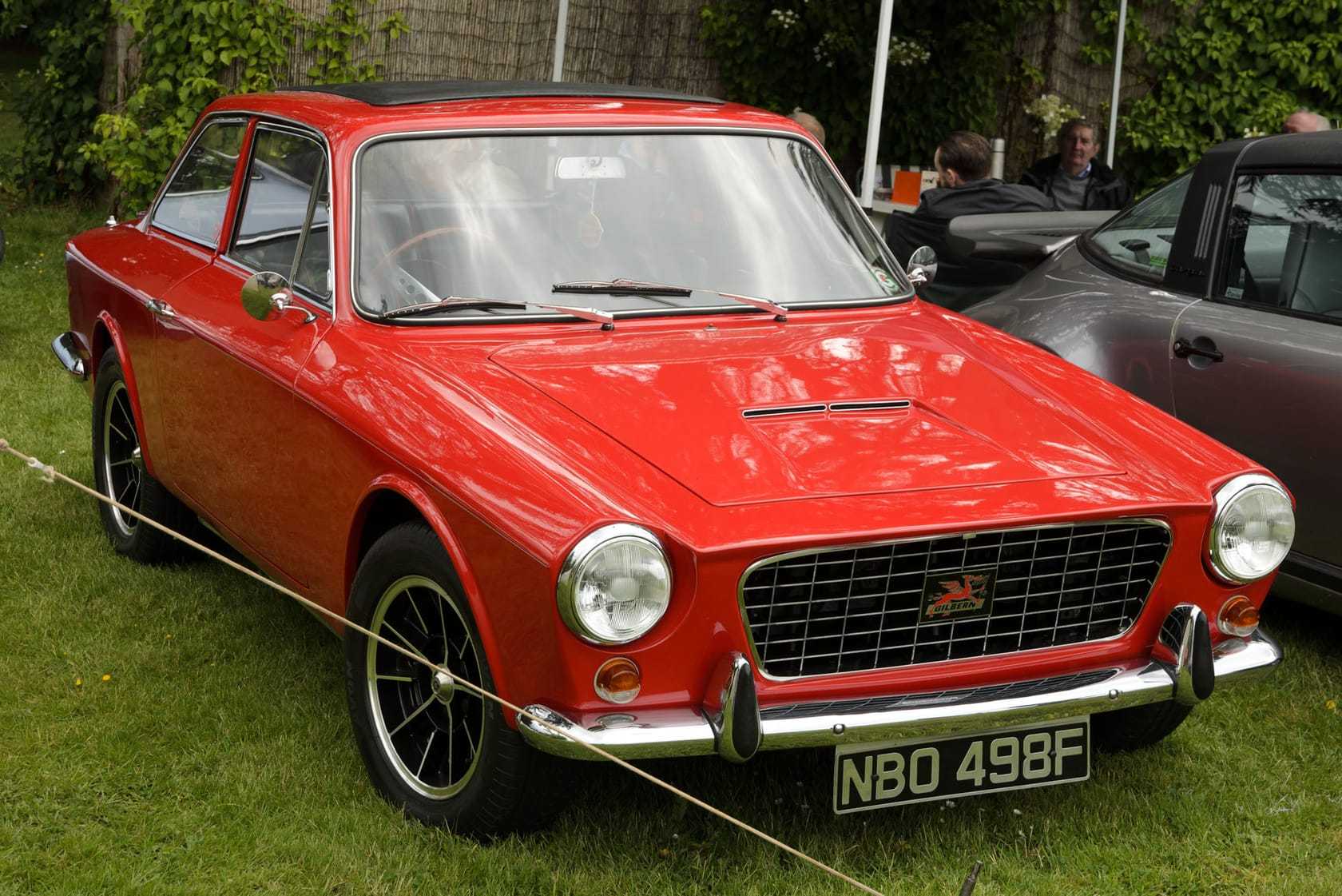 A red Gilbern Genie coupe, registration NBO 498F, front three-quarter view at a classic car show