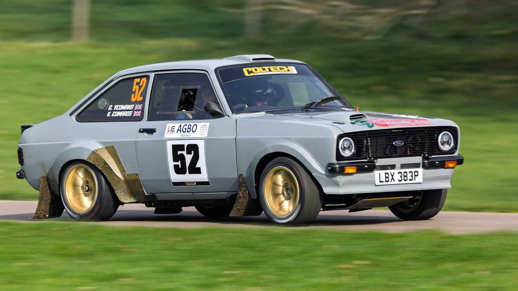 A grey Ford Escort Mk2 rally car with flared arches sliding through a corner on a stage