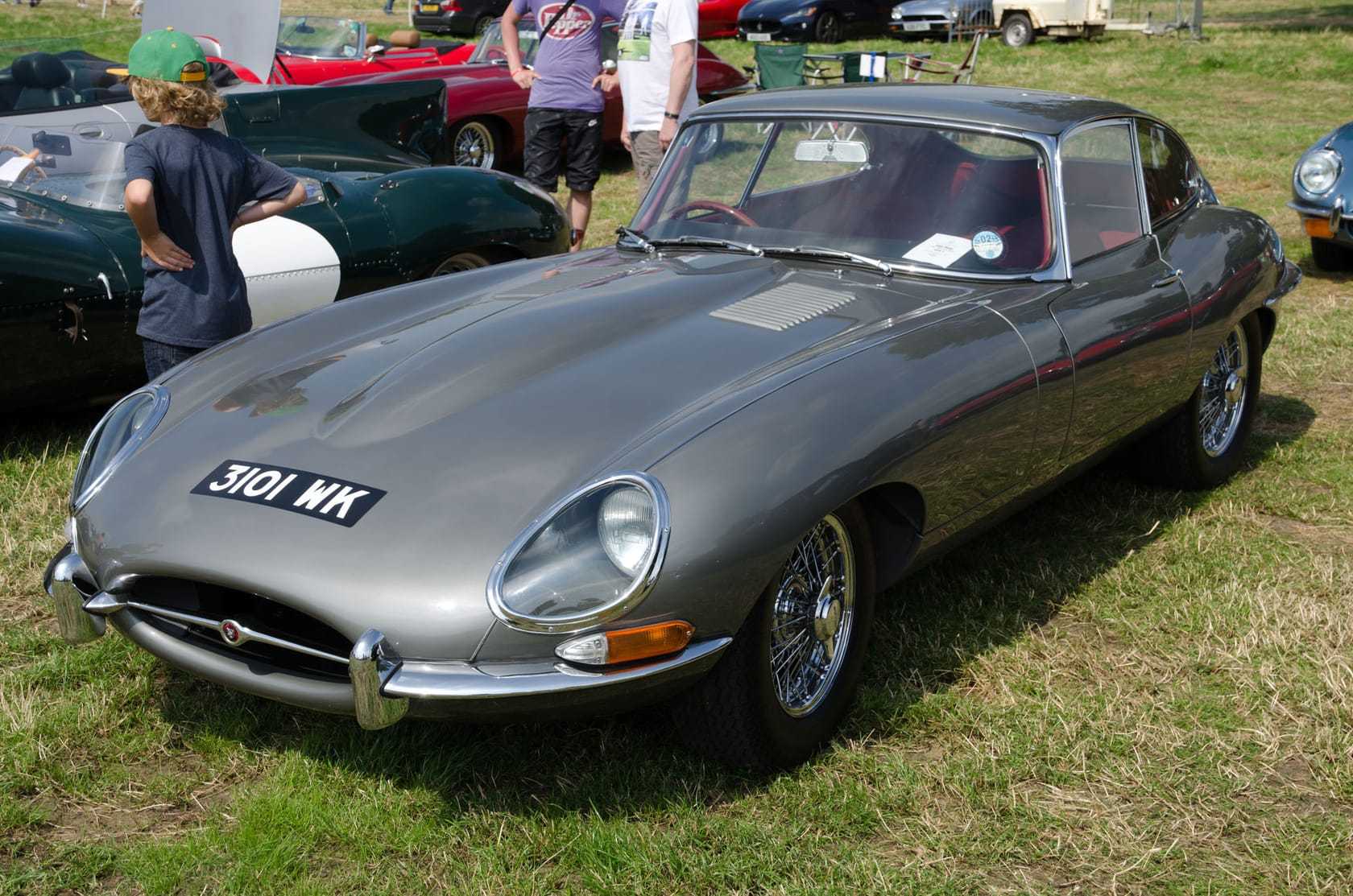 A grey 1962 Jaguar E-Type Series 1 fixed-head coupe with UK registration 3101 WK, front three-quarter view showing covered headlamps
