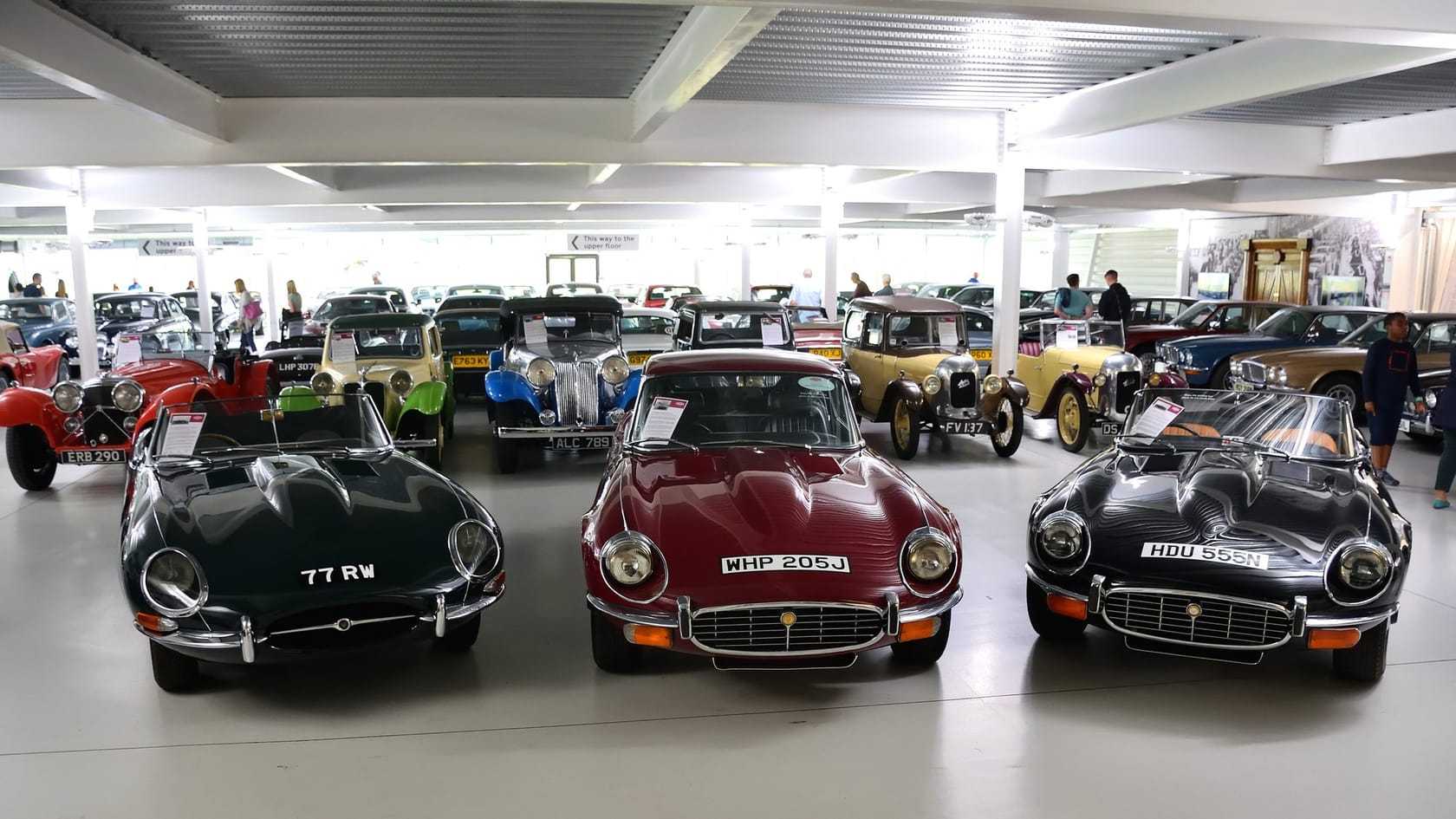 A line of Jaguar E-Types, from an early roadster to a late V12, on display in a hall at the British Motor Museum, Gaydon