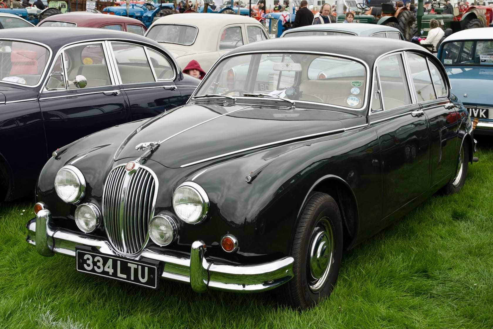 A dark green 1960 Jaguar Mk2 3.8 with chrome wire wheels and a UK registration on a show field