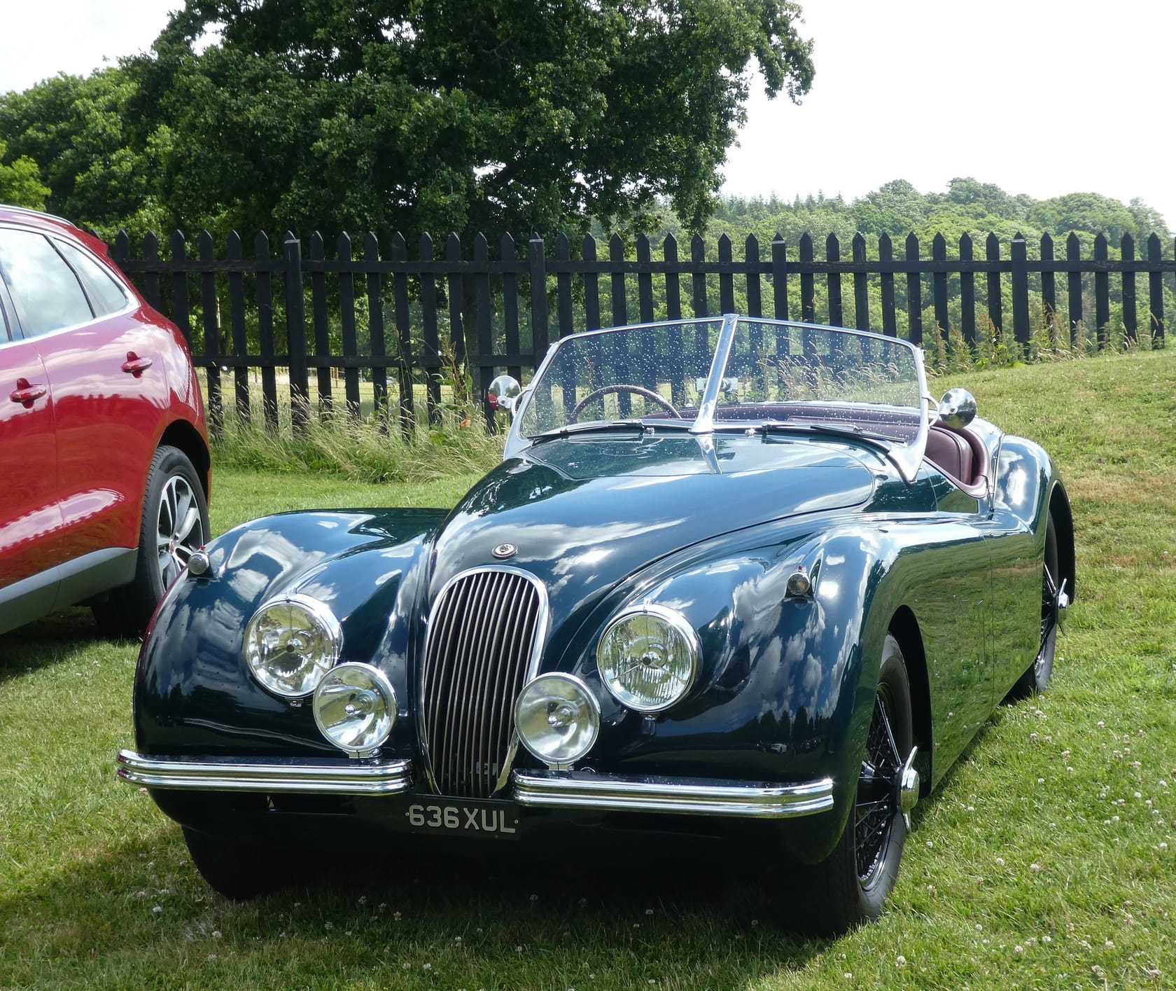 A dark green Jaguar XK120 open roadster on grass, front three-quarter view, UK registration 636 XUL