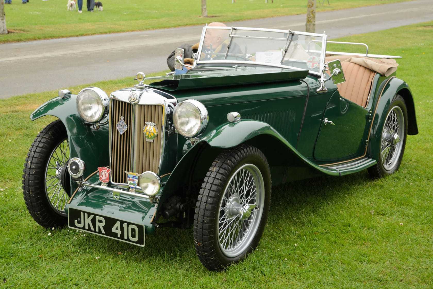 A dark green 1947 MG TC with a UK registration and wire wheels on a show field, its hood down