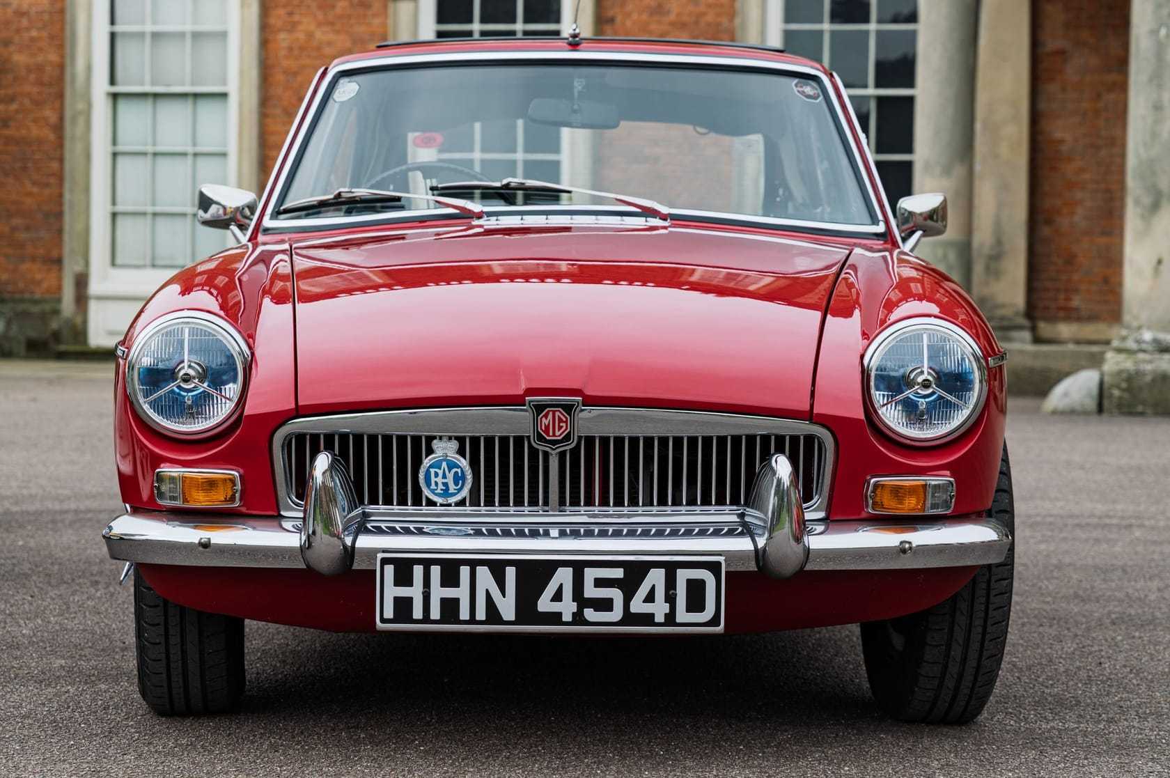 A red MGB GT seen head-on, chrome grille and MG octagon badge, UK registration HHN 454D