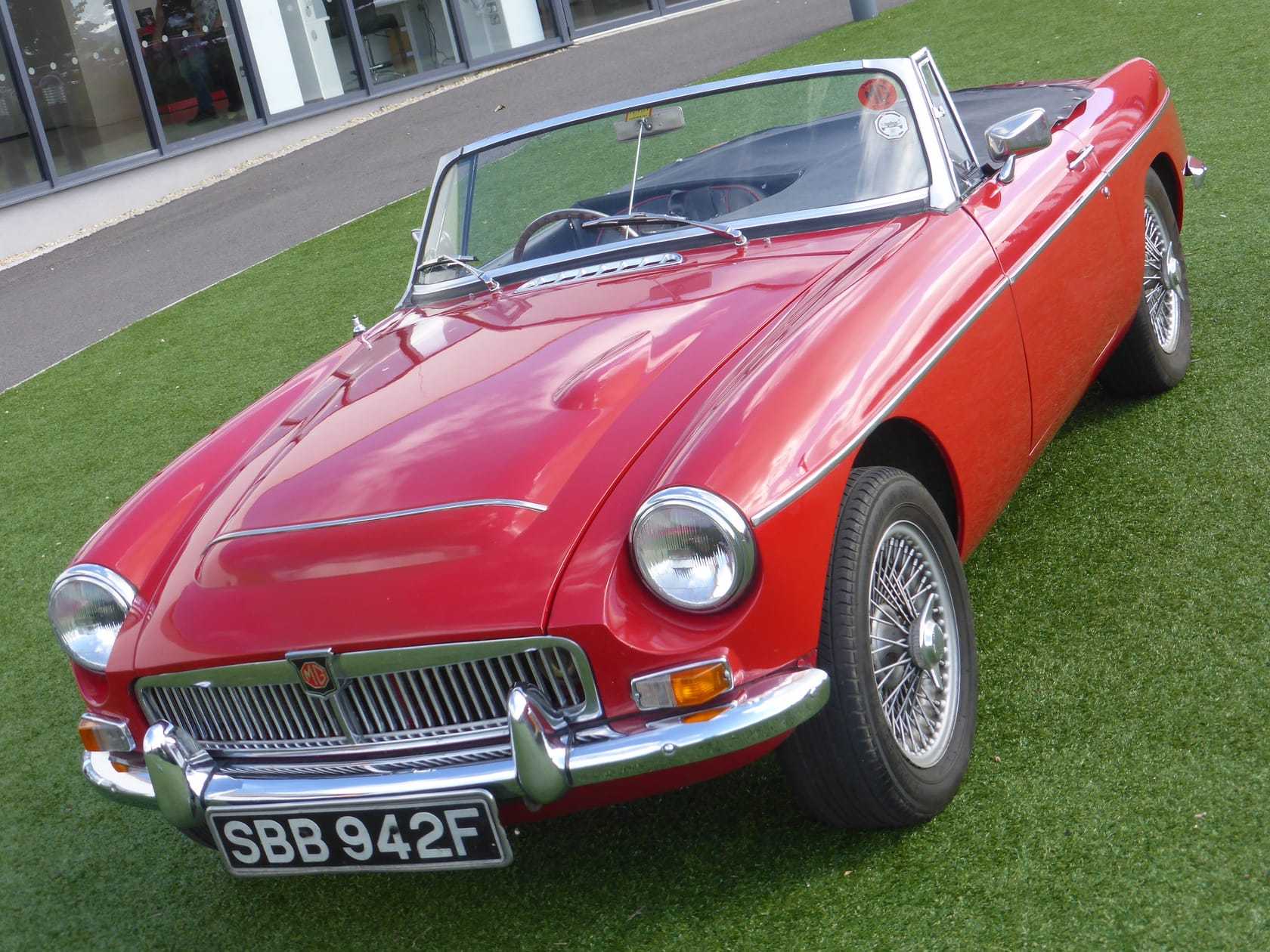 A red MG MGC roadster with wire wheels, top down, front three-quarter view