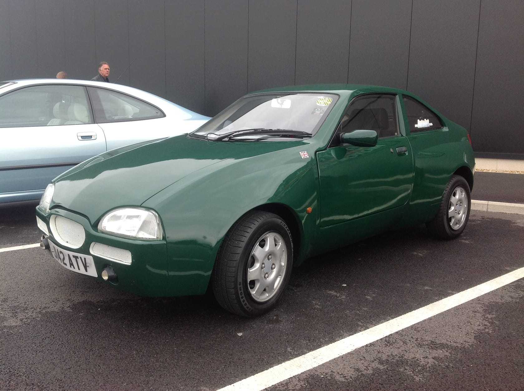 A dark green Midas coupe based on Austin Rover Metro components, parked in a car park with a UK registration