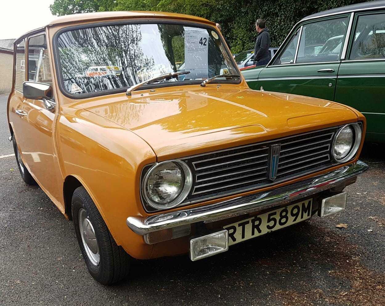An orange Mini Clubman saloon at a show, front three-quarter view