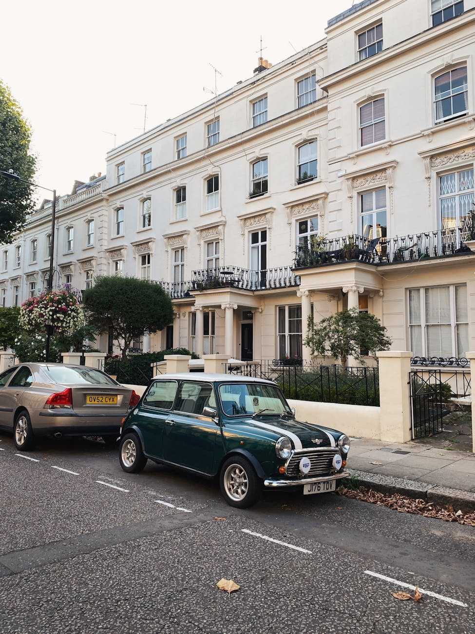 A green Mini Cooper with a white roof parked on a London terrace street