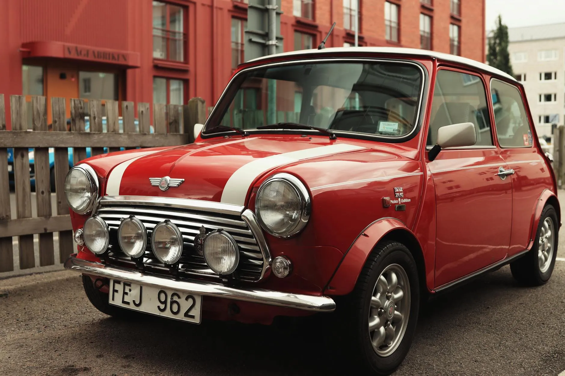 A red Mini Cooper with a white roof and driving lamps, front three-quarter view