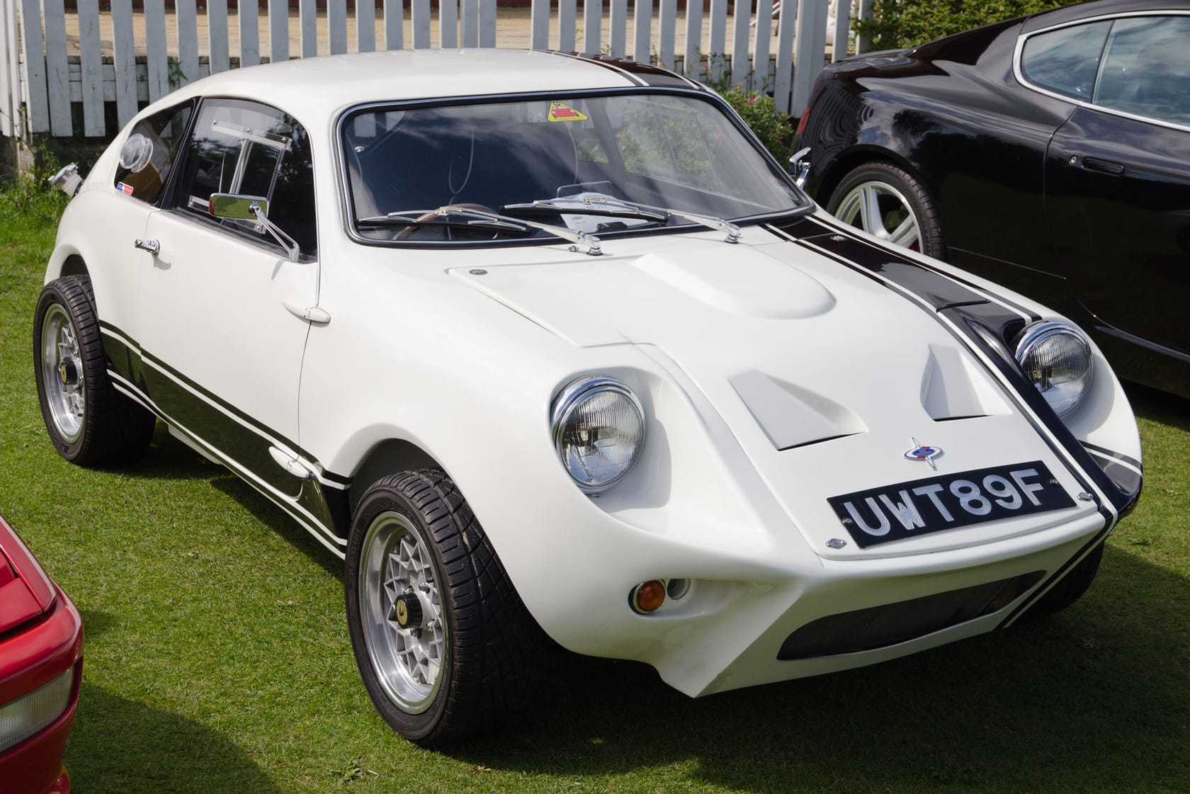 A white 1968 Mini Marcos coupe, front three-quarter view at an outdoor classic car show