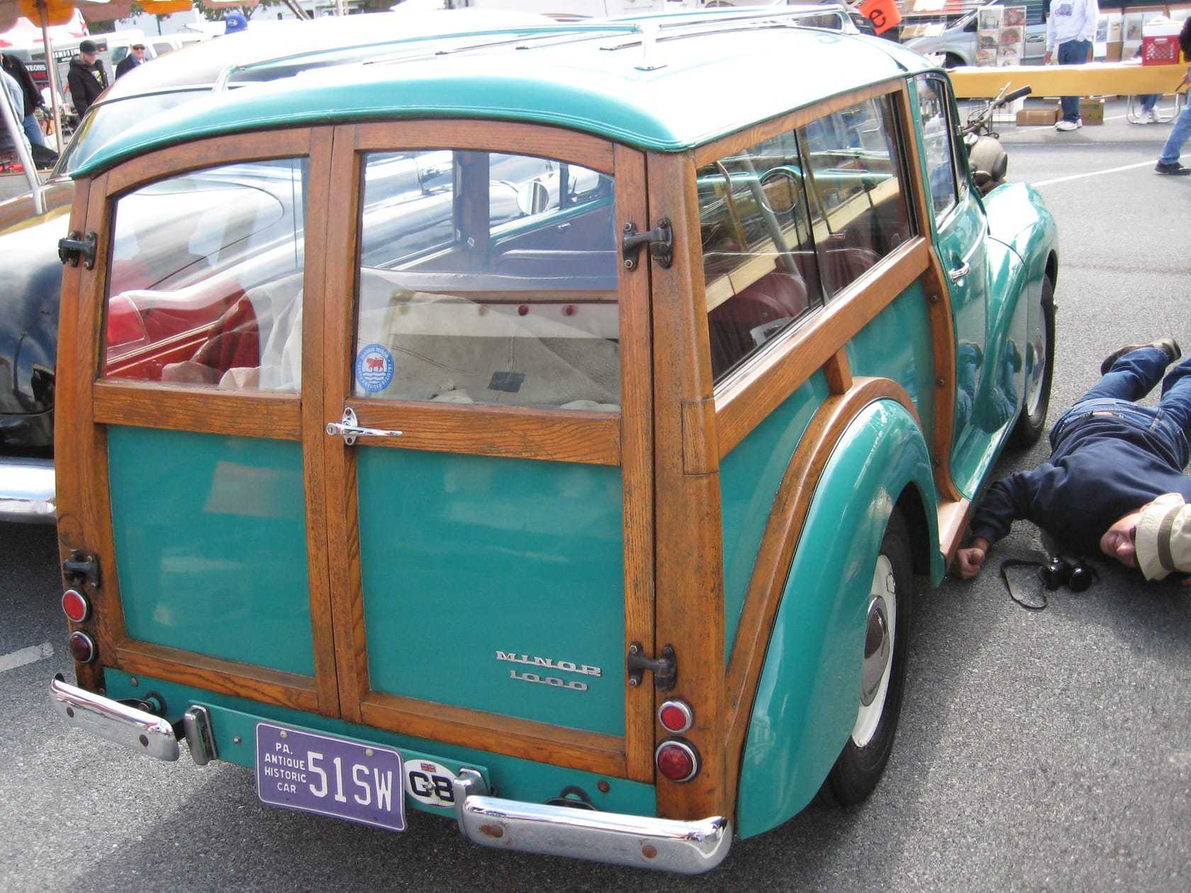 A cream Morris Minor saloon with a red interior parked at the roadside
