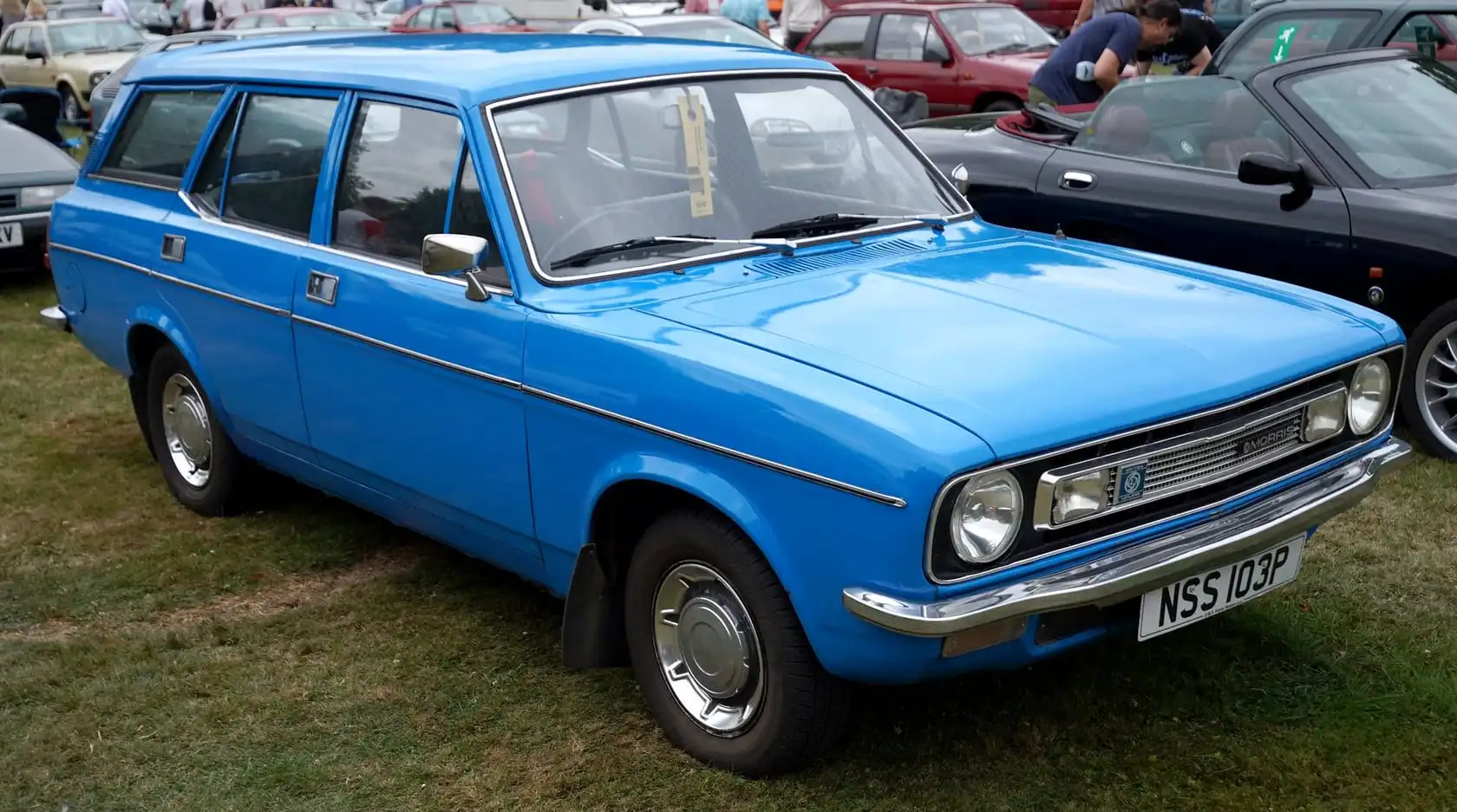 A bright blue Morris Marina 1.8 SDL Estate (1975–76, NSS103P plate), front three-quarter view on grass at a classic car show