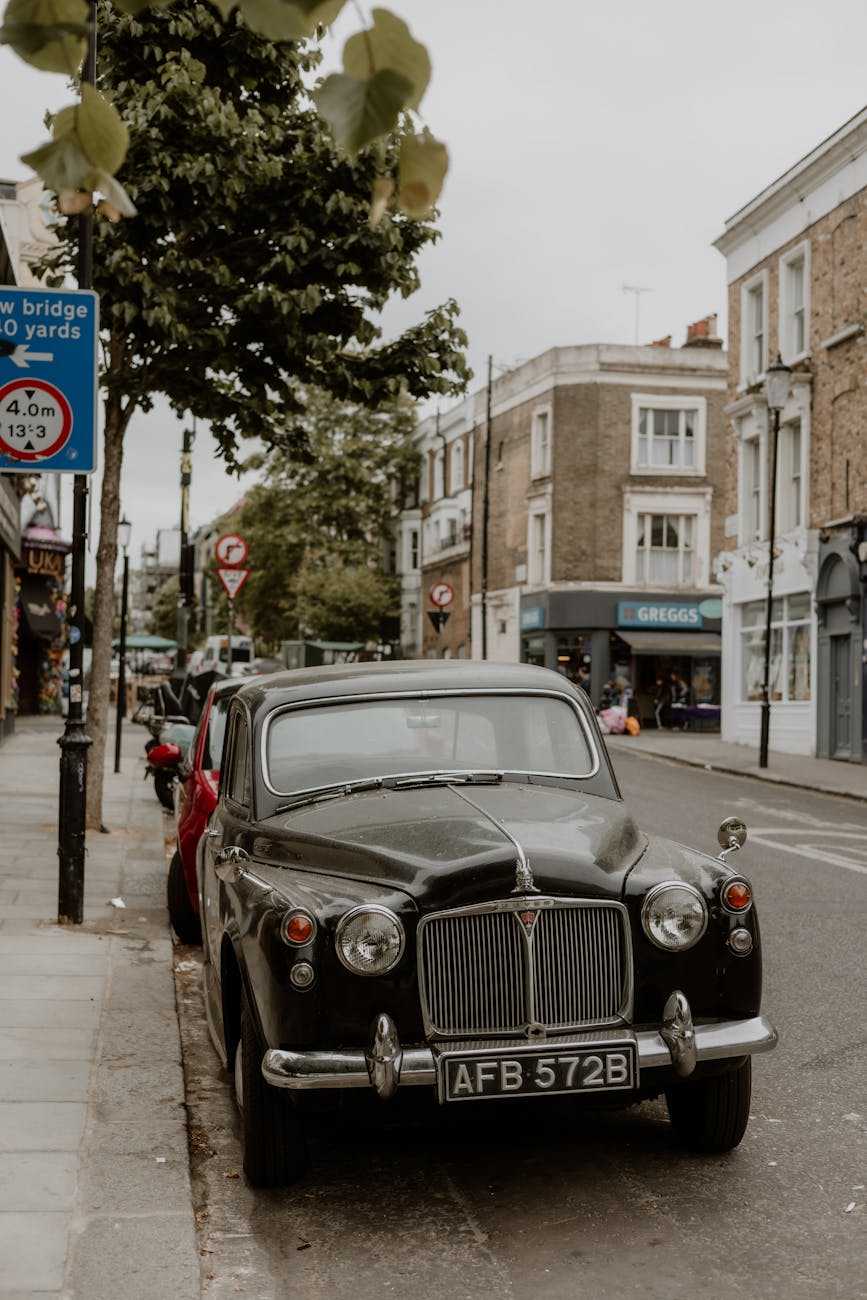A black Rover P4 saloon parked at the kerb on a London street lined with terraced houses
