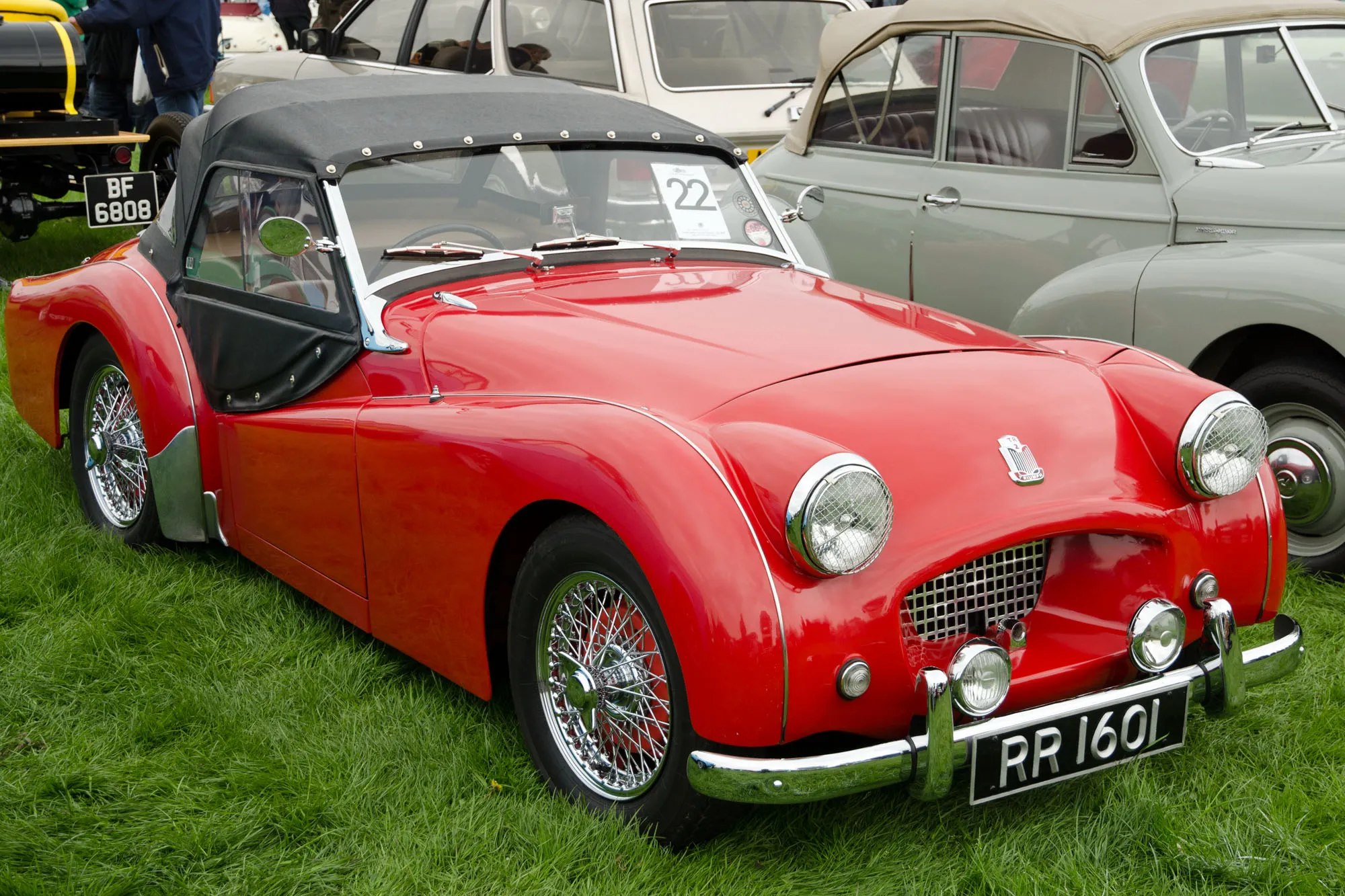 A red Triumph TR2 with the hood up, UK registration RR 1601, front three-quarter view on a show field
