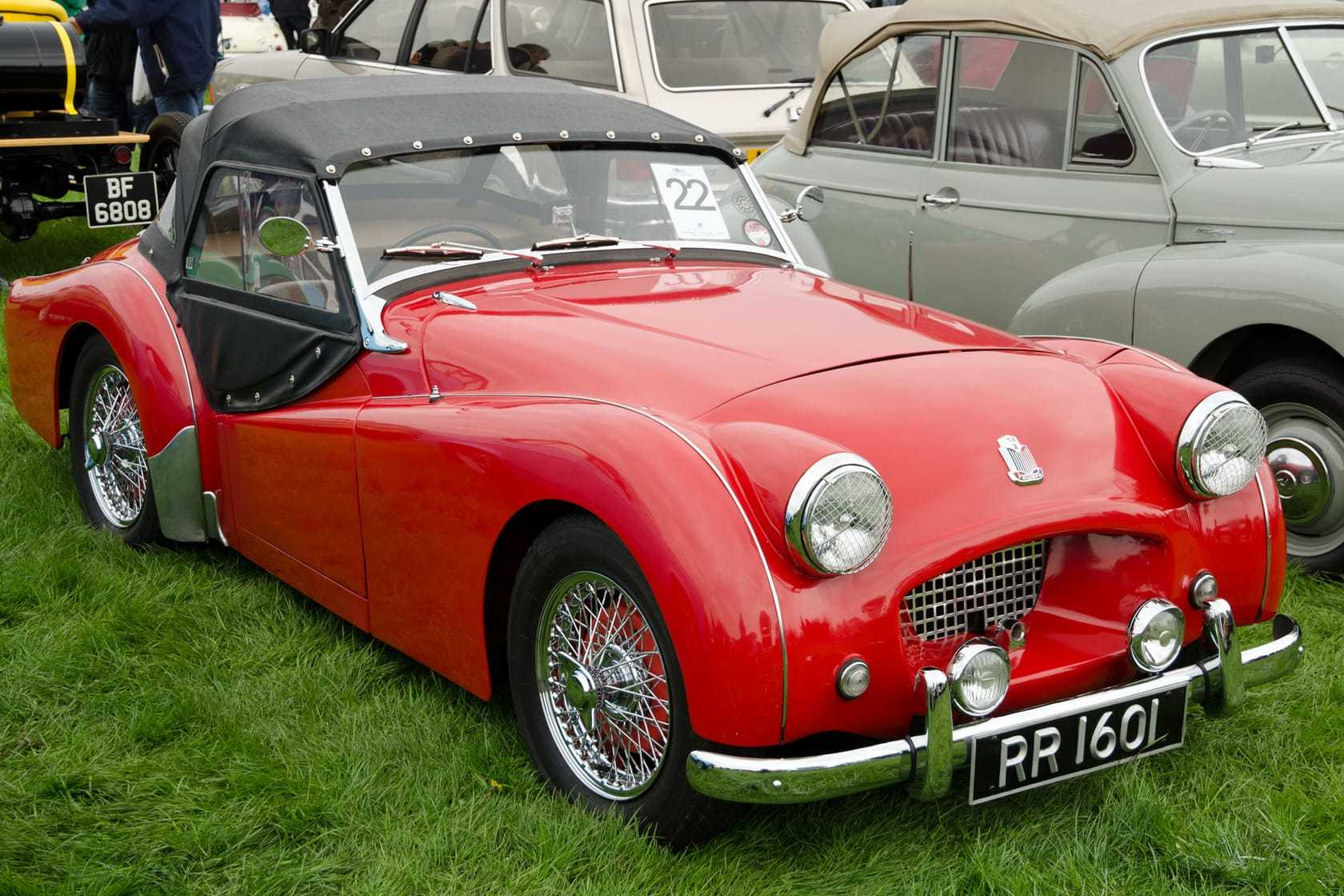 A red Triumph TR2 with the hood up, UK registration RR 1601, front three-quarter view on a show field