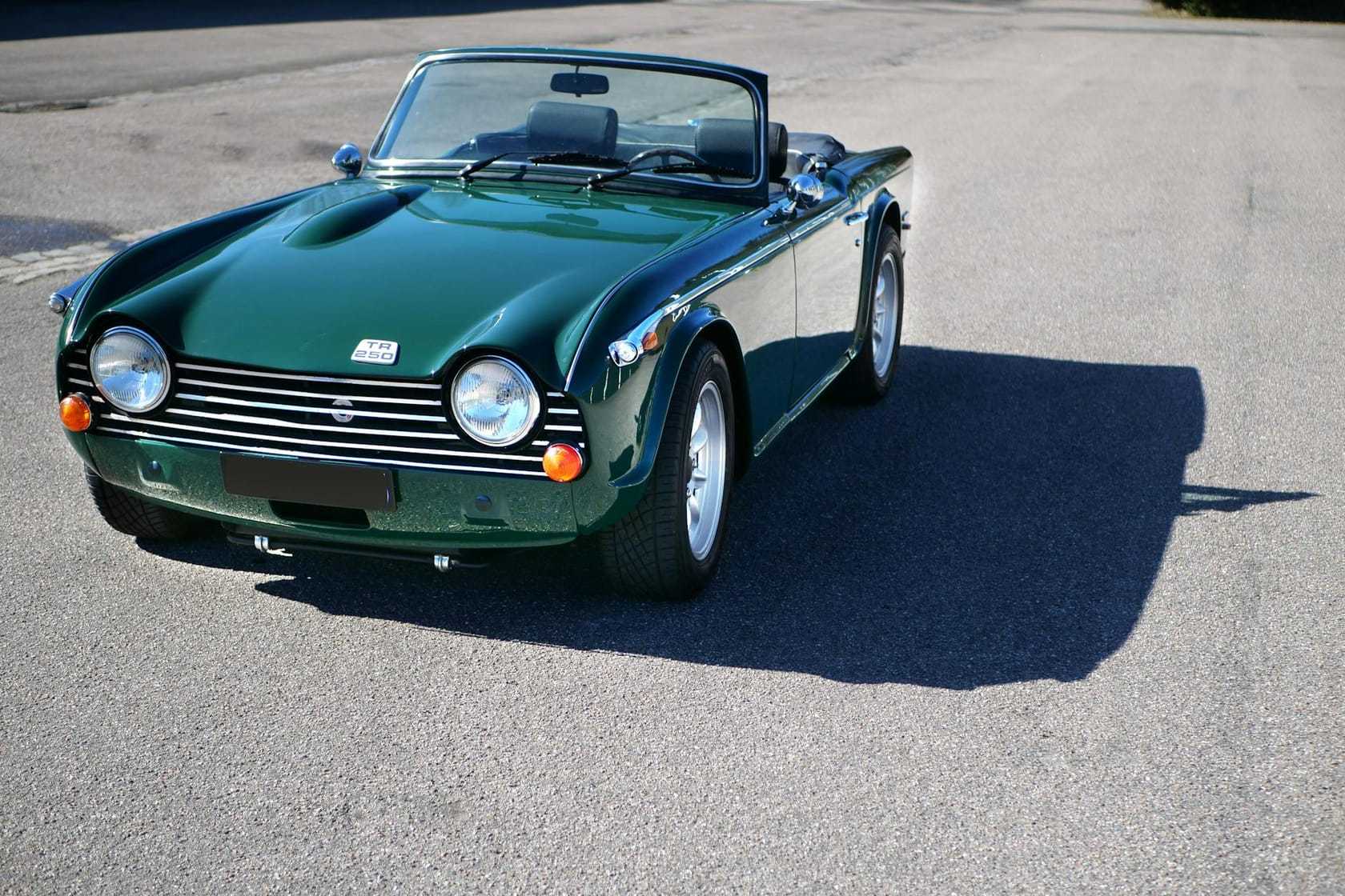 A British Racing Green Triumph TR4 roadster with the top down, front three-quarter view