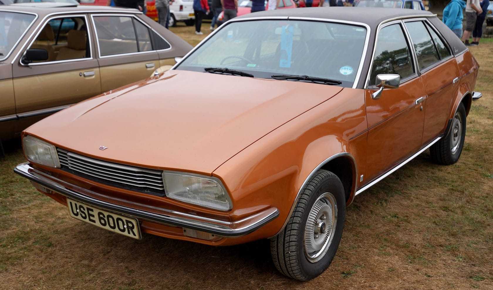 A bright orange Austin Princess wedge saloon (R plate, 1976–77) with black vinyl roof, front three-quarter view at an outdoor classic car show