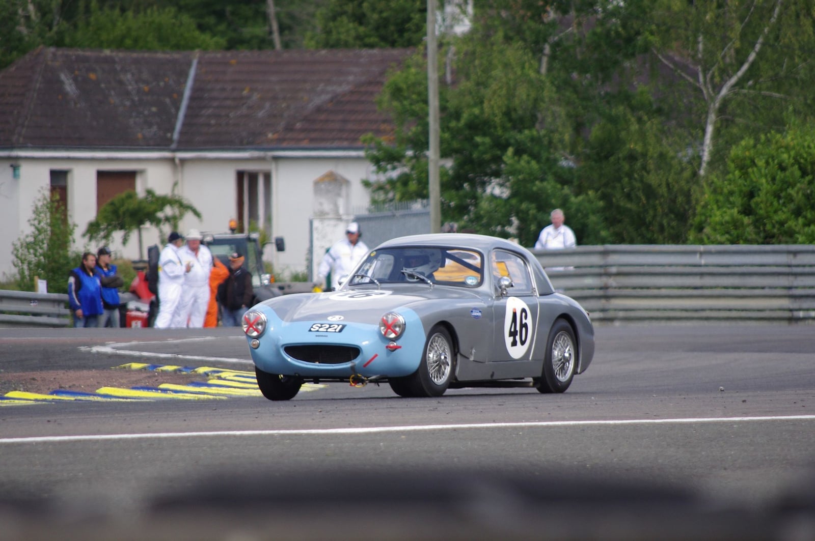 A green Sebring Sprite racing on a circuit