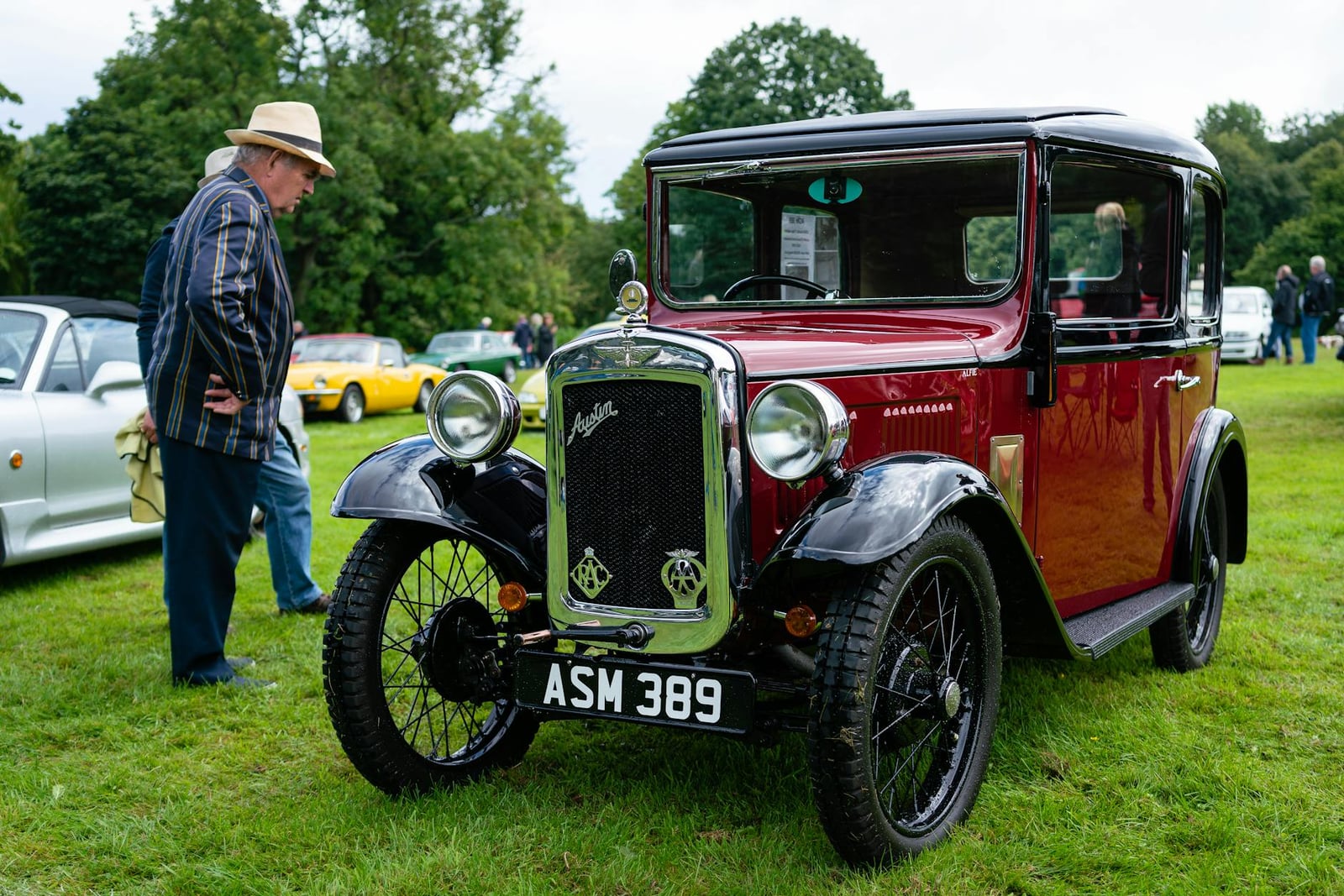 A maroon Austin Seven Ruby saloon at a show, front three-quarter view, UK registration ASM 389