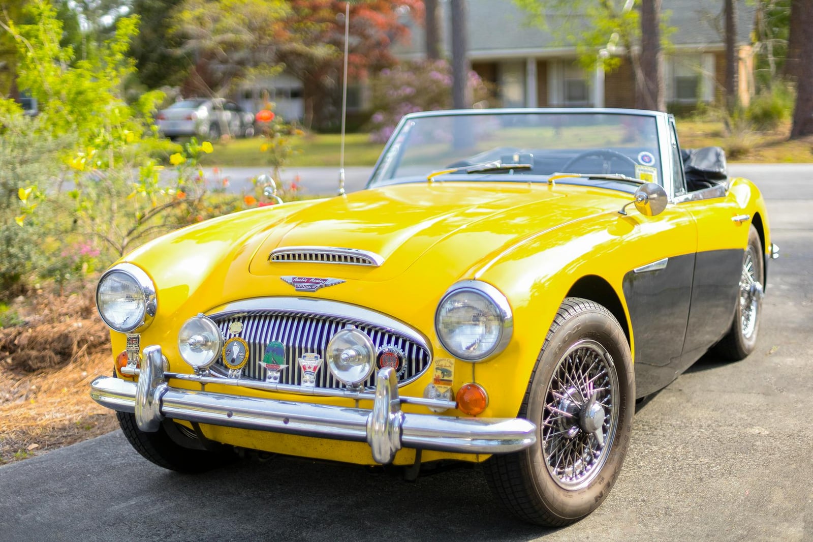 A bright yellow Austin-Healey 3000 convertible parked outdoors
