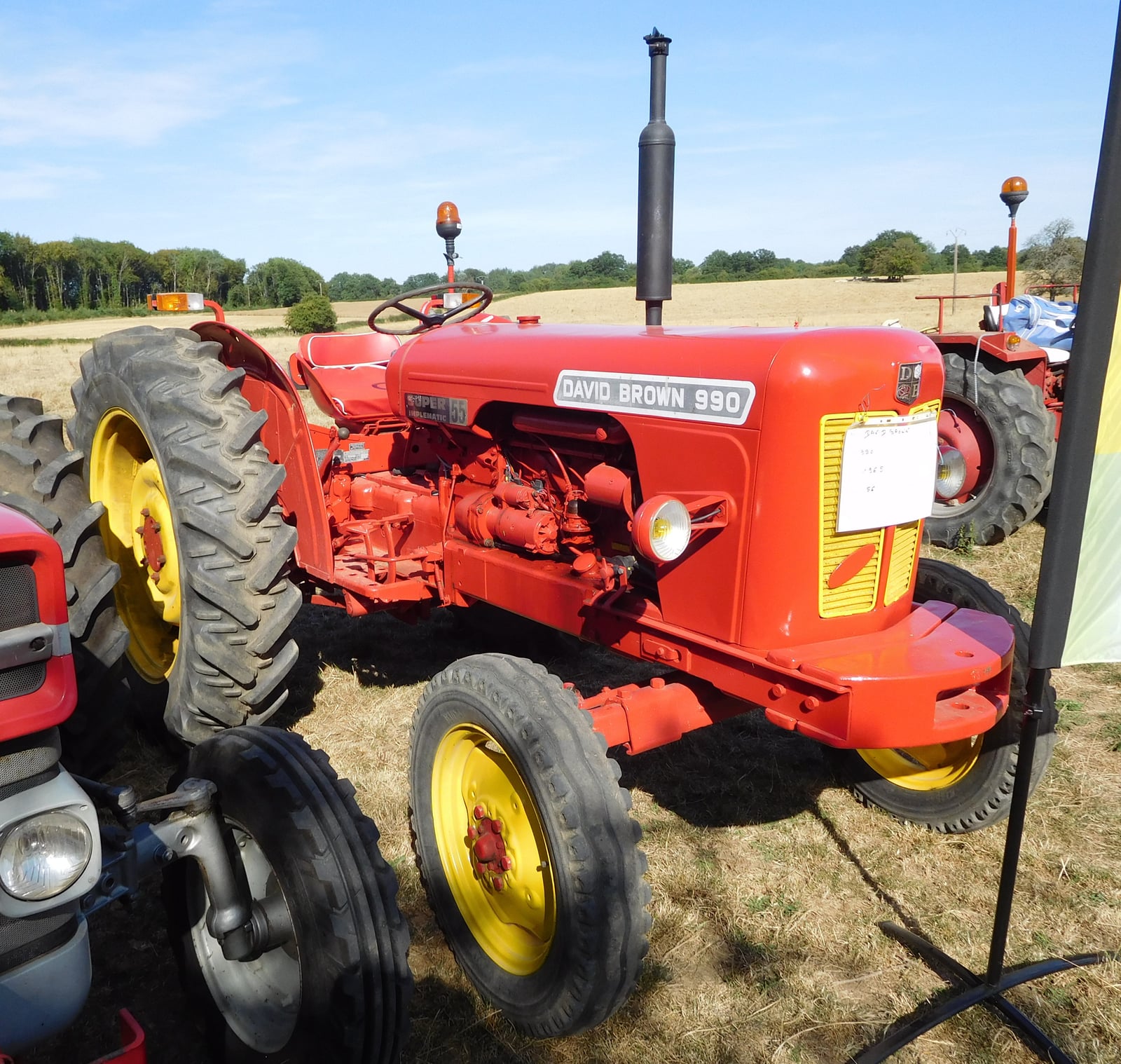 A restored bright red and yellow David Brown 990, the 990 name on the bonnet, at a show