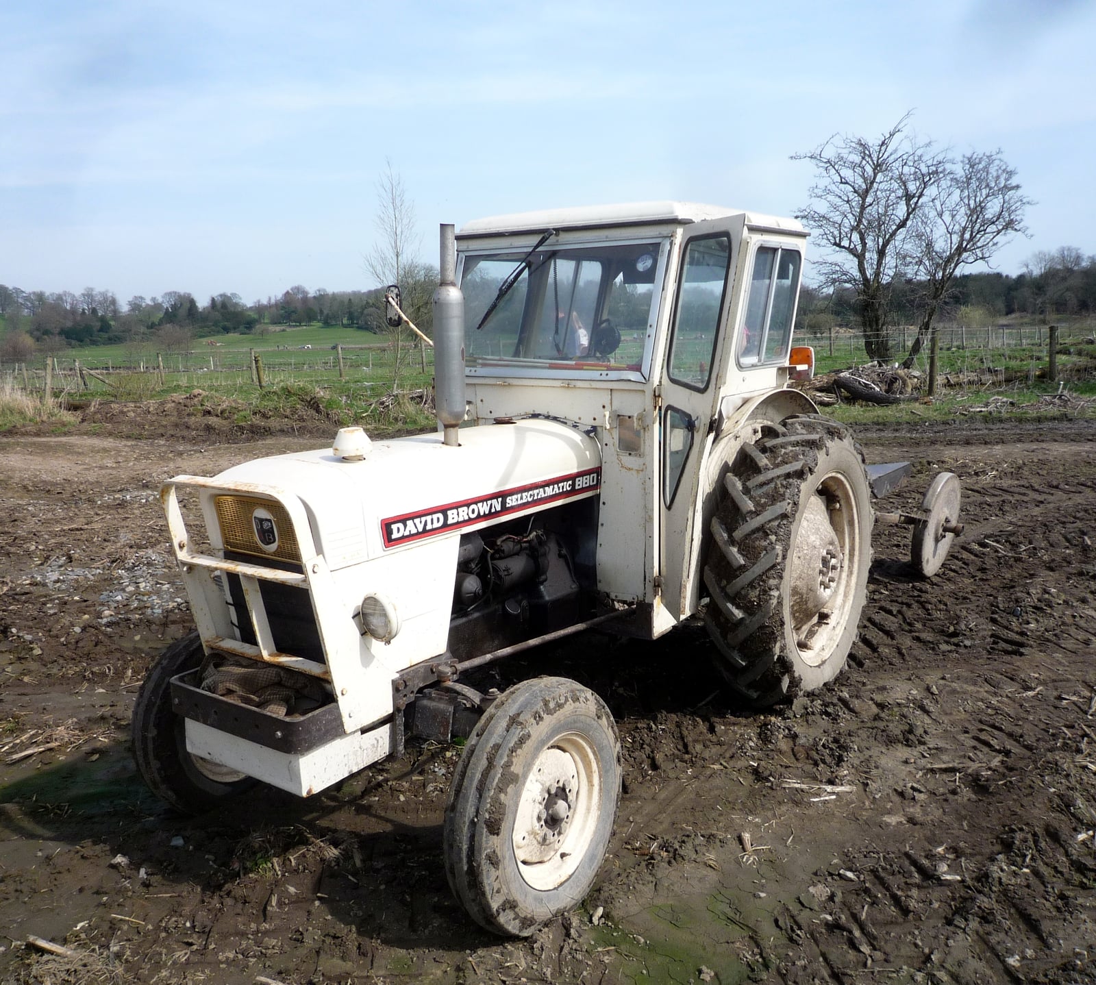 A white David Brown Selectamatic 880 with a cab ploughing a muddy field