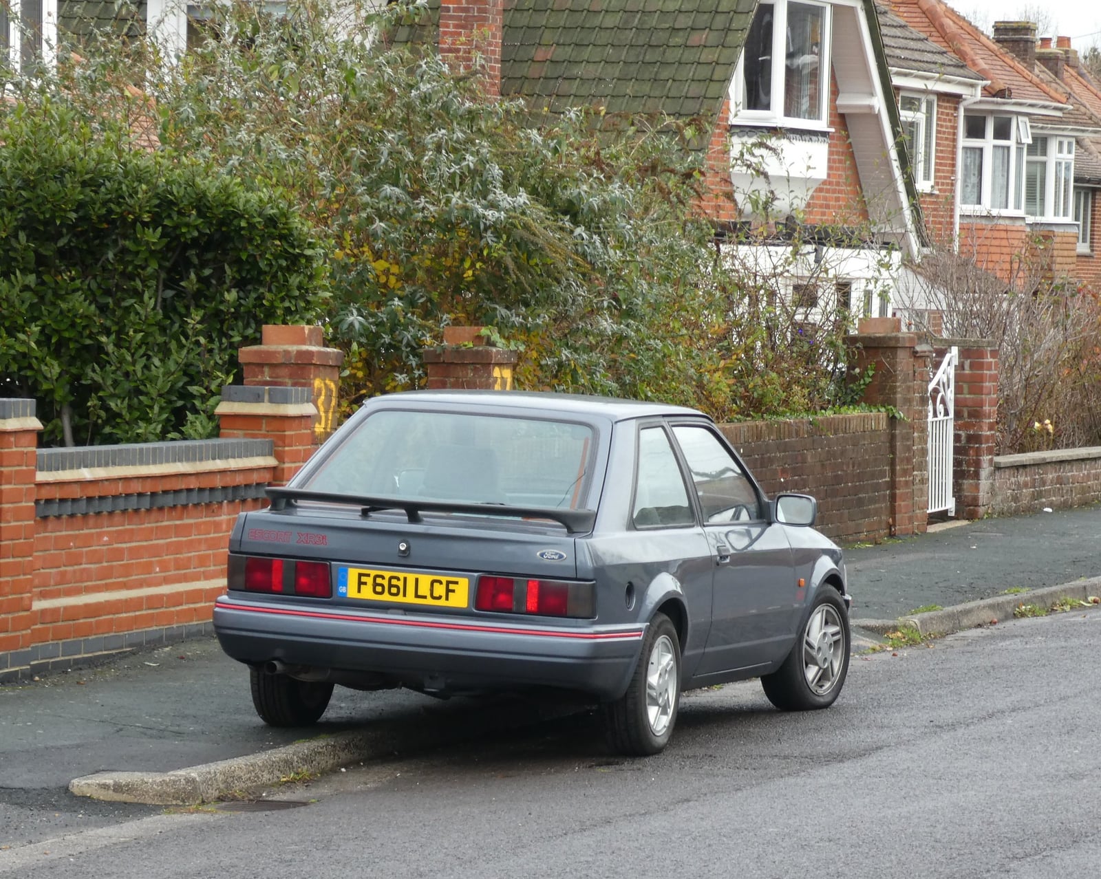 A grey Ford Escort XR3i hatchback parked on a residential street, rear three-quarter view