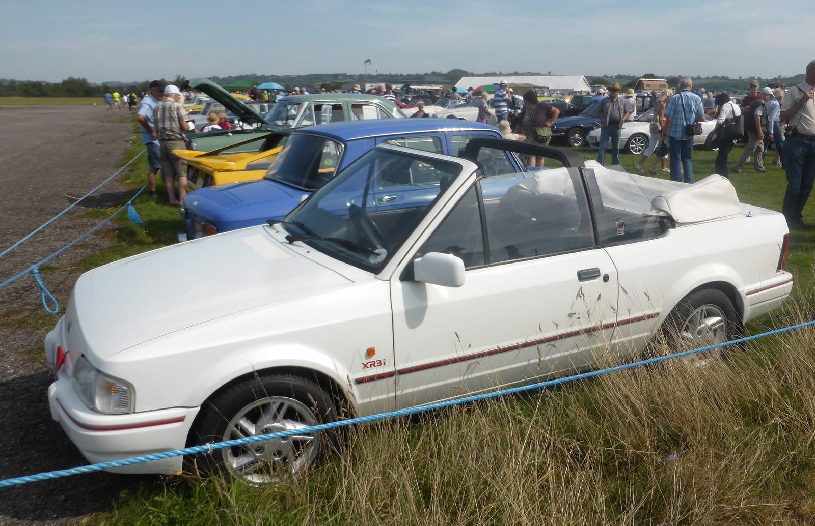 A white Ford Escort XR3i cabriolet at an airfield show, side view
