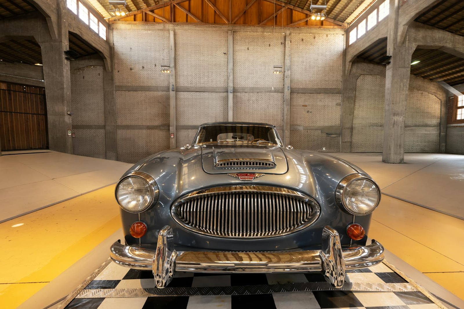 A vintage Austin-Healey roadster shown head-on in a classic car display