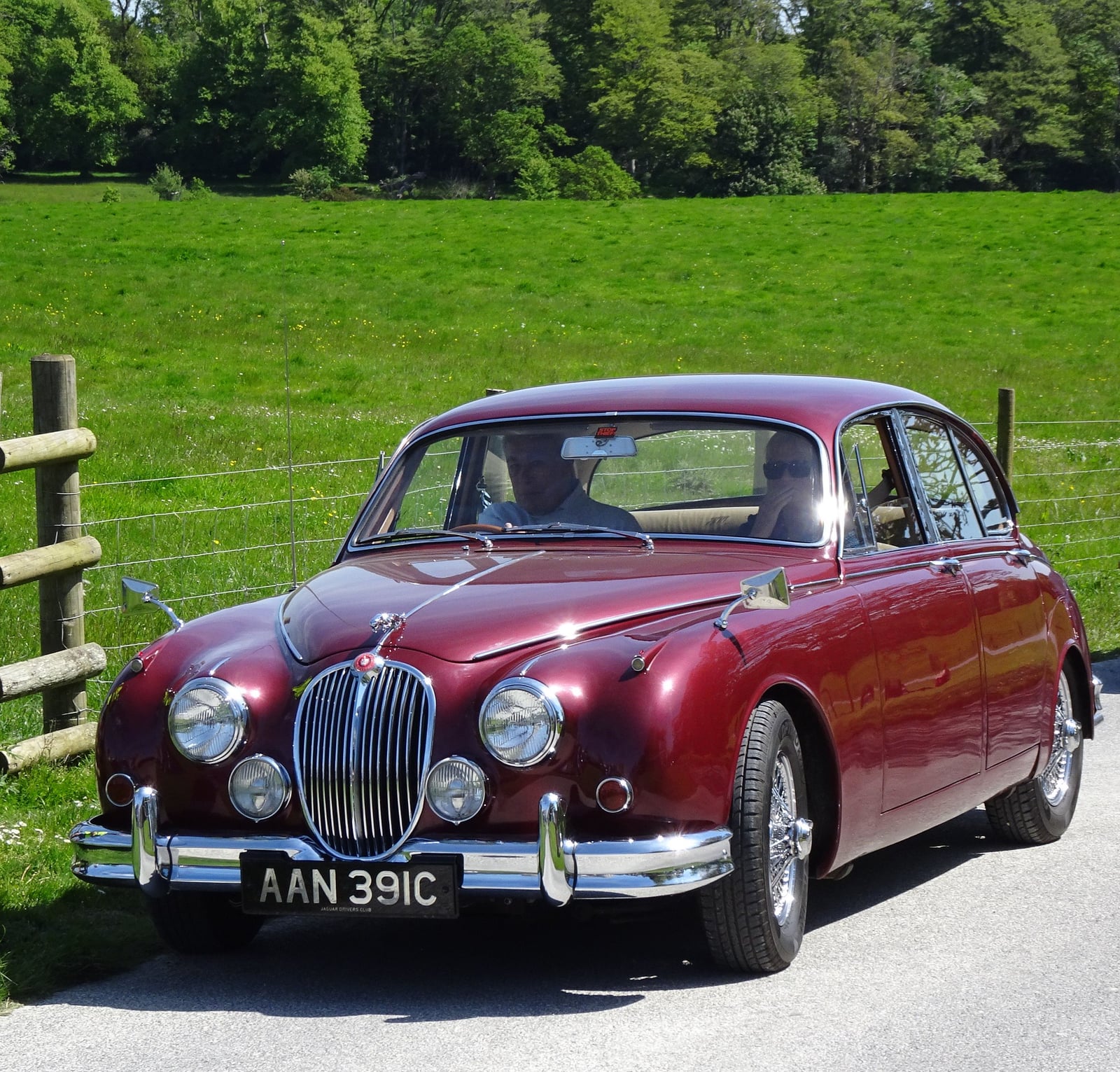 A maroon Jaguar Mk2 saloon, front three-quarter view on a country road, showing the grille, wings, bonnet and bumpers