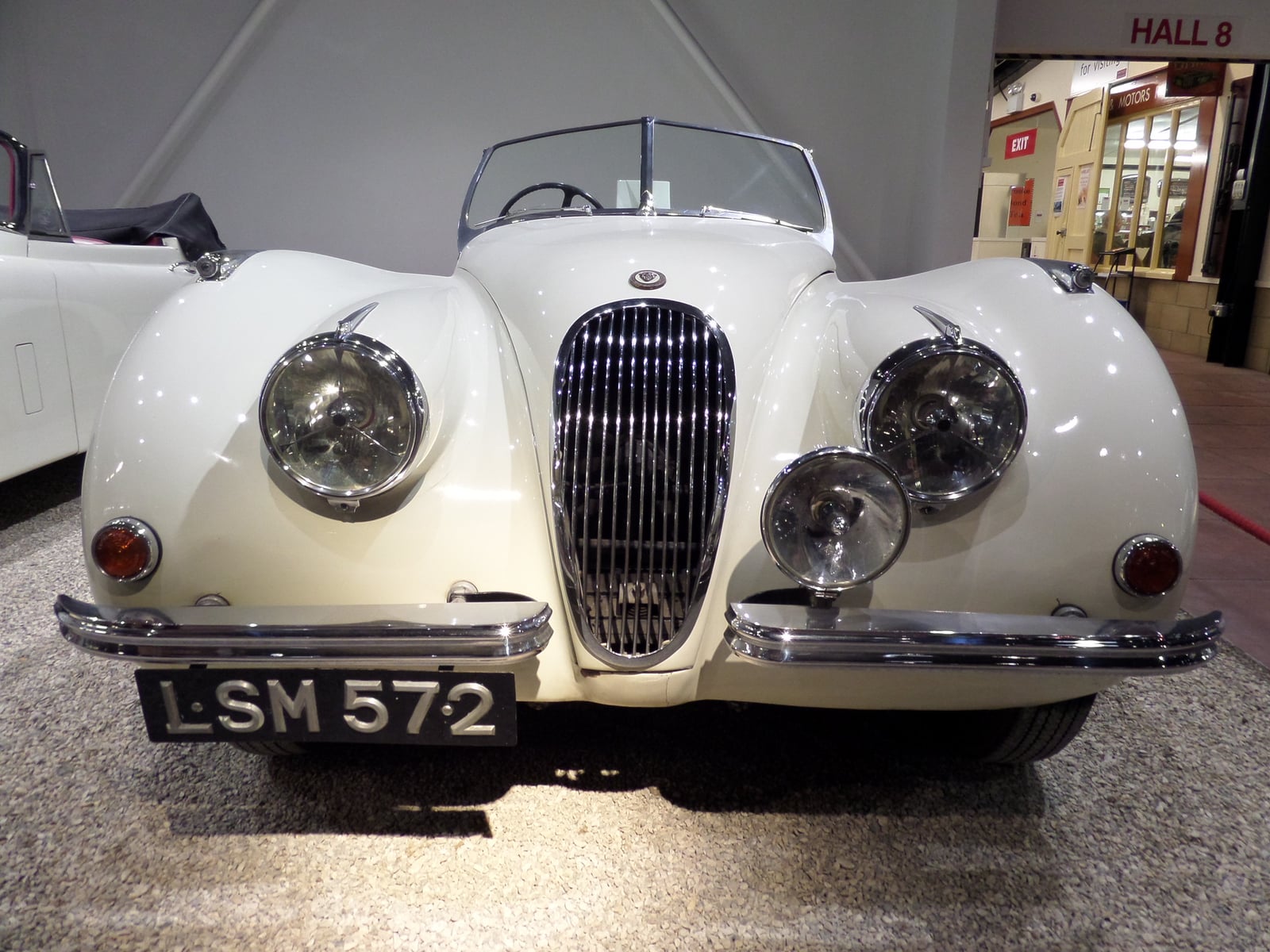 A cream Jaguar XK120 open roadster seen head-on, slatted chrome grille and faired-in headlamps, UK registration LSM 572