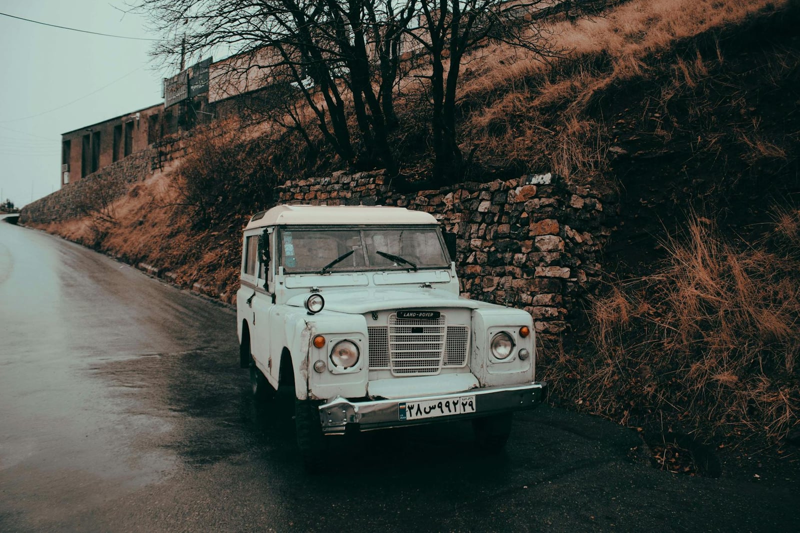 A white Land Rover Series III parked on a wet roadside