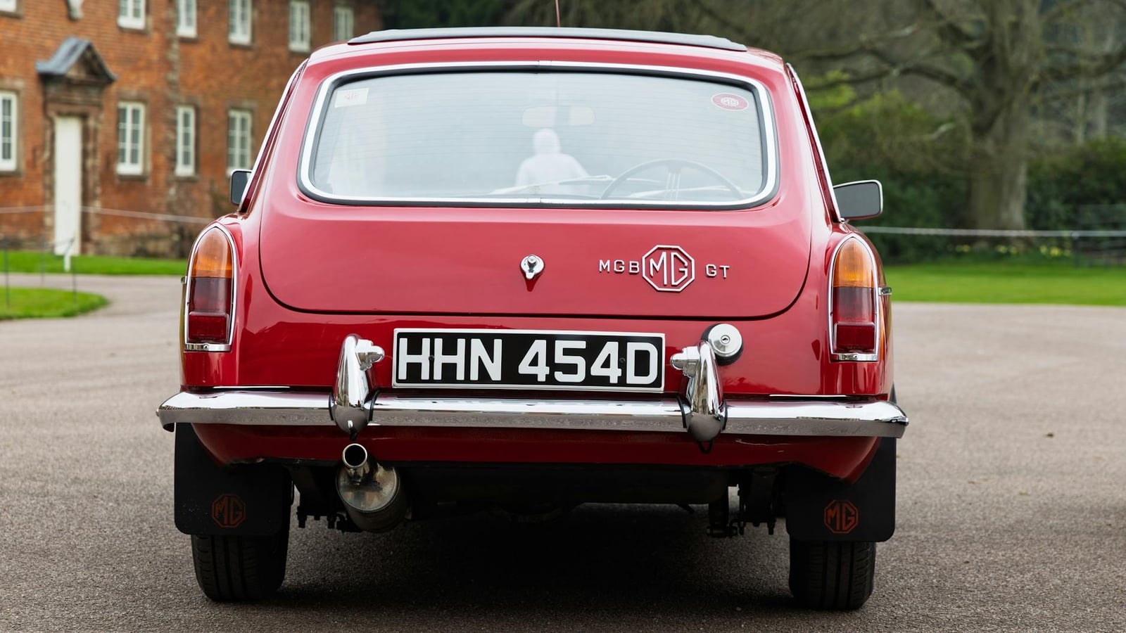 The rear of a red MG MGB GT, showing the hatchback tailgate, rear screen surround and MG GT badge