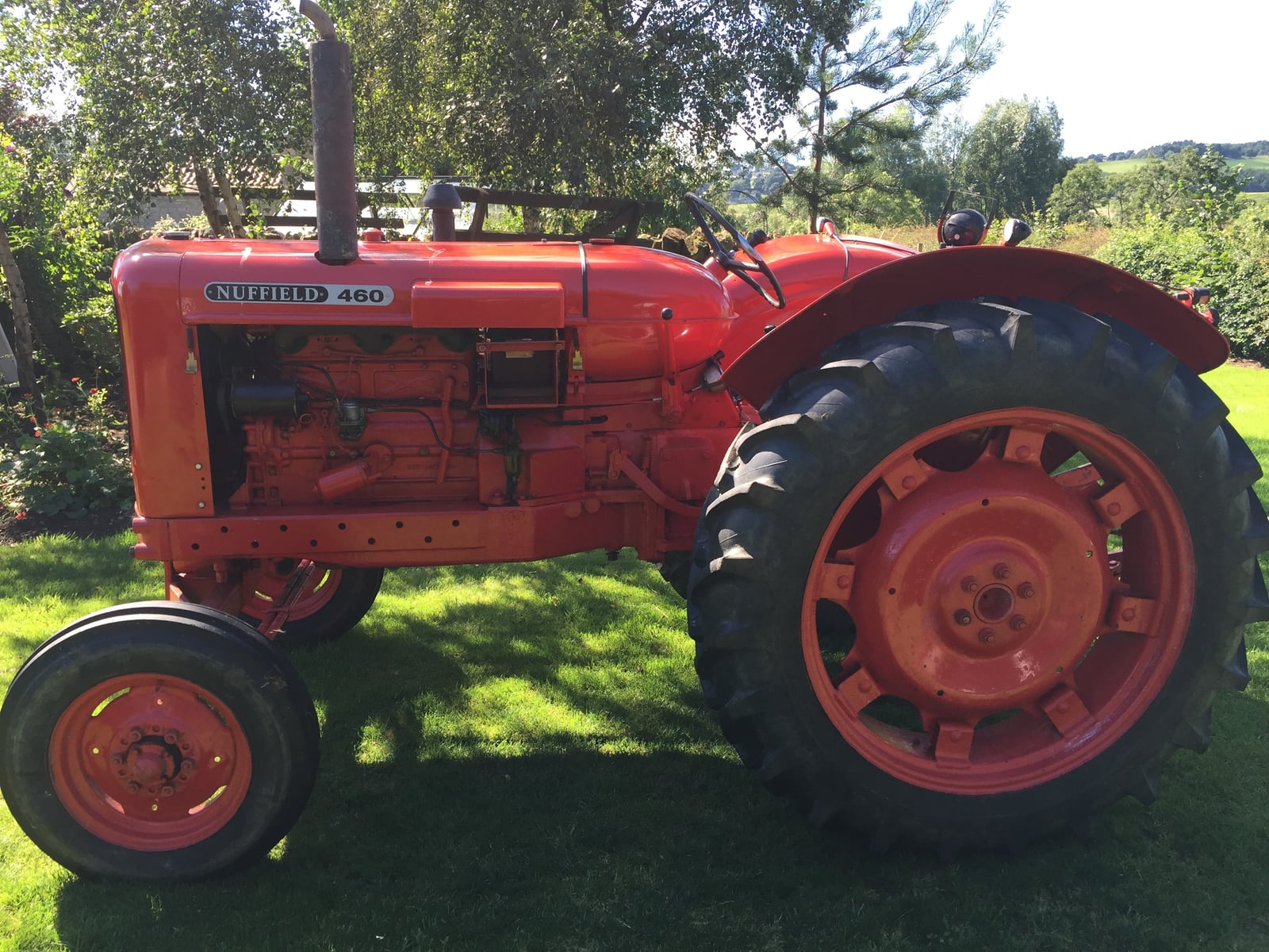 A glossy orange Nuffield 460 tractor in side profile on a lawn